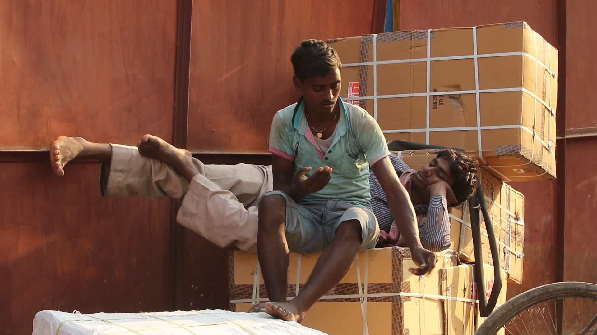 Daily wage worker takes rest on bundles of goods 
