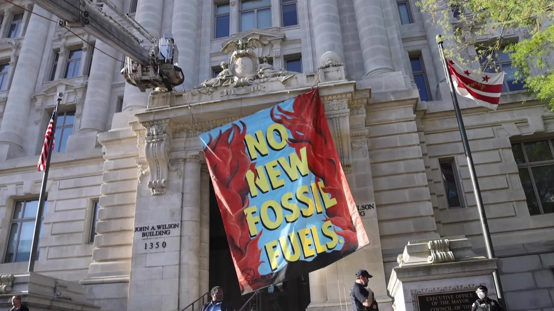Climate activist scales Wilson Building and drops banner