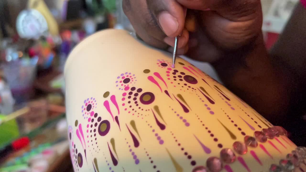 Artist carefully paints a vase with a dot art design