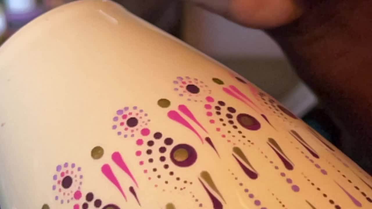 Artist carefully paints a vase with a dot art design