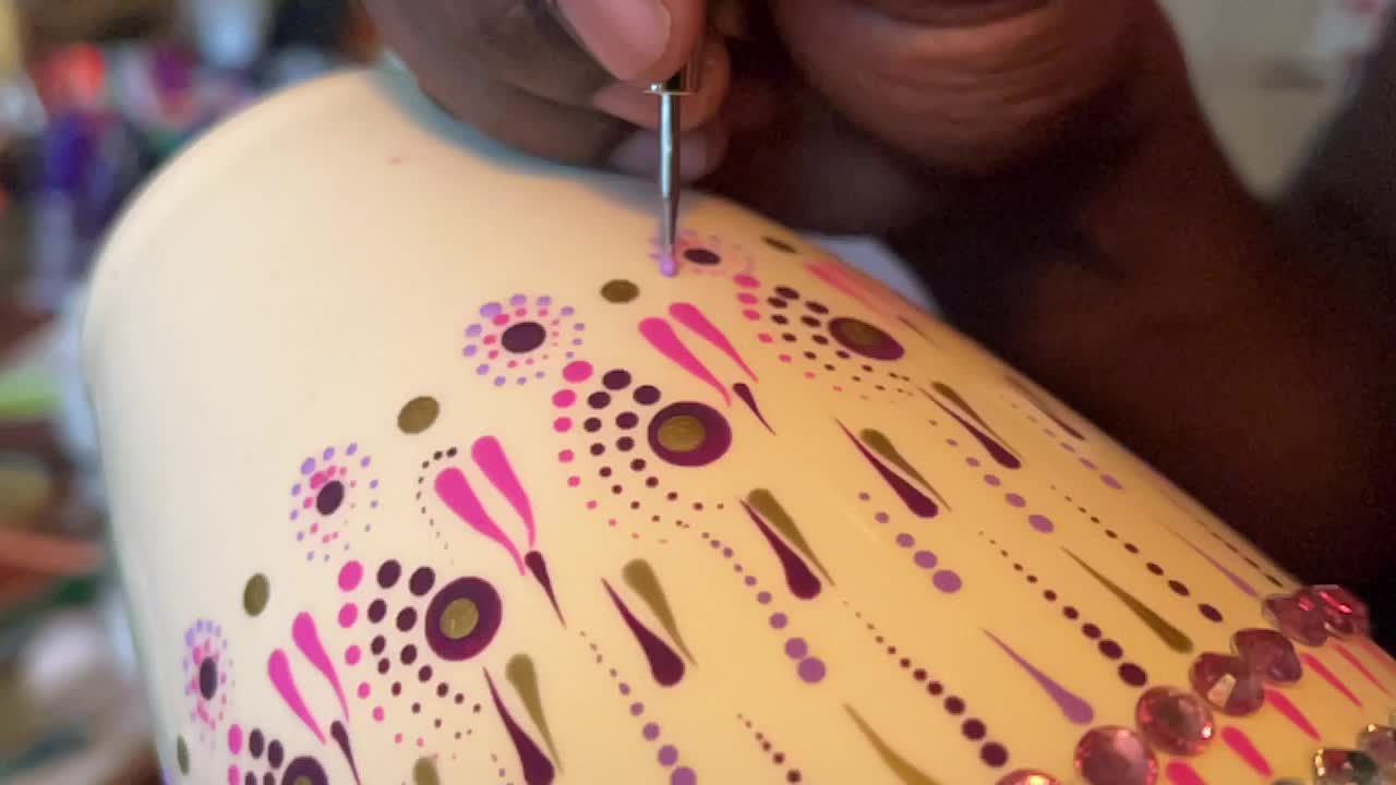 Artist carefully paints a vase with a dot art design