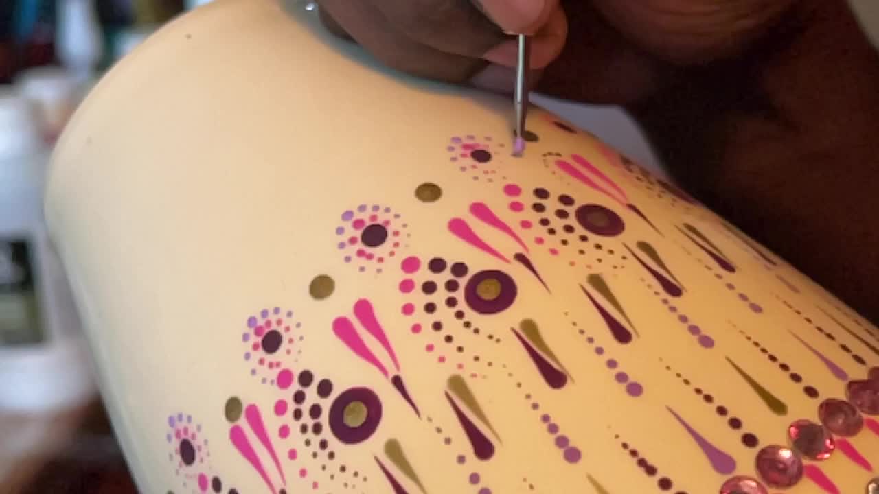 Artist carefully paints a vase with a dot art design