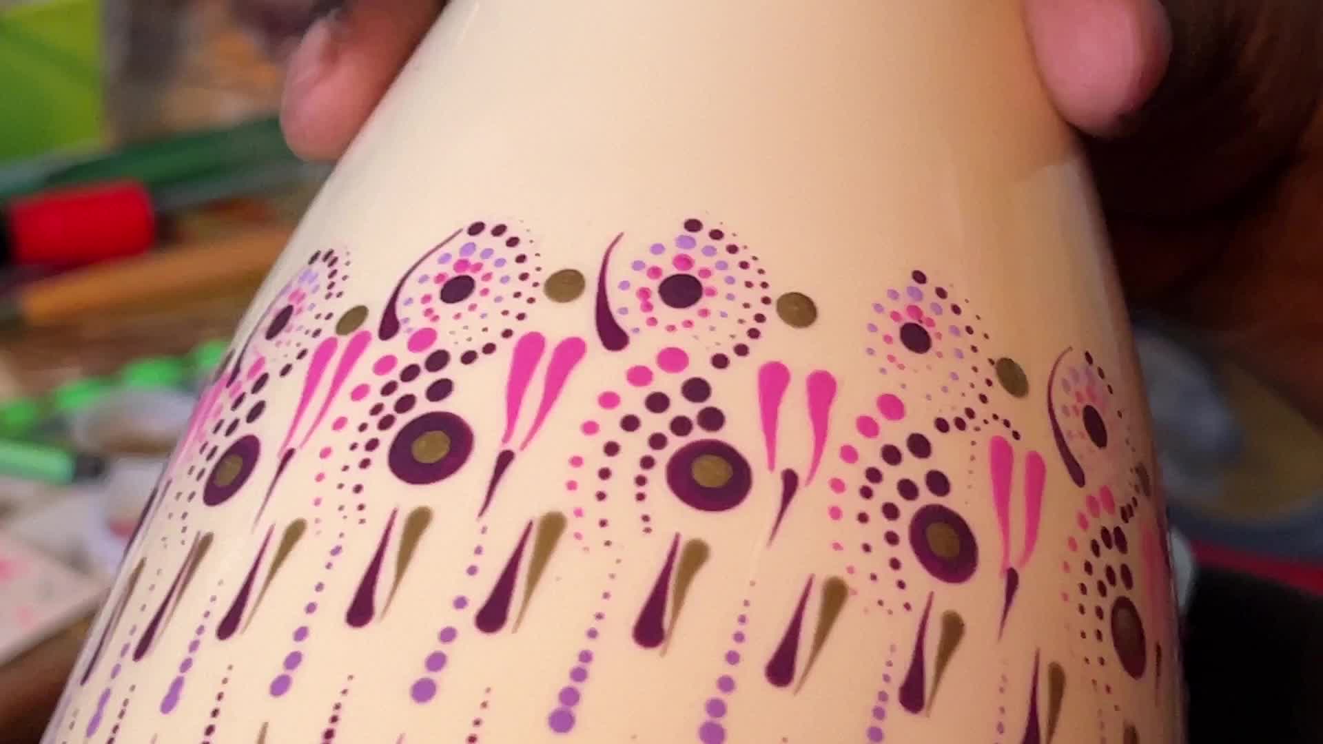 Artist carefully paints a vase with a dot art design