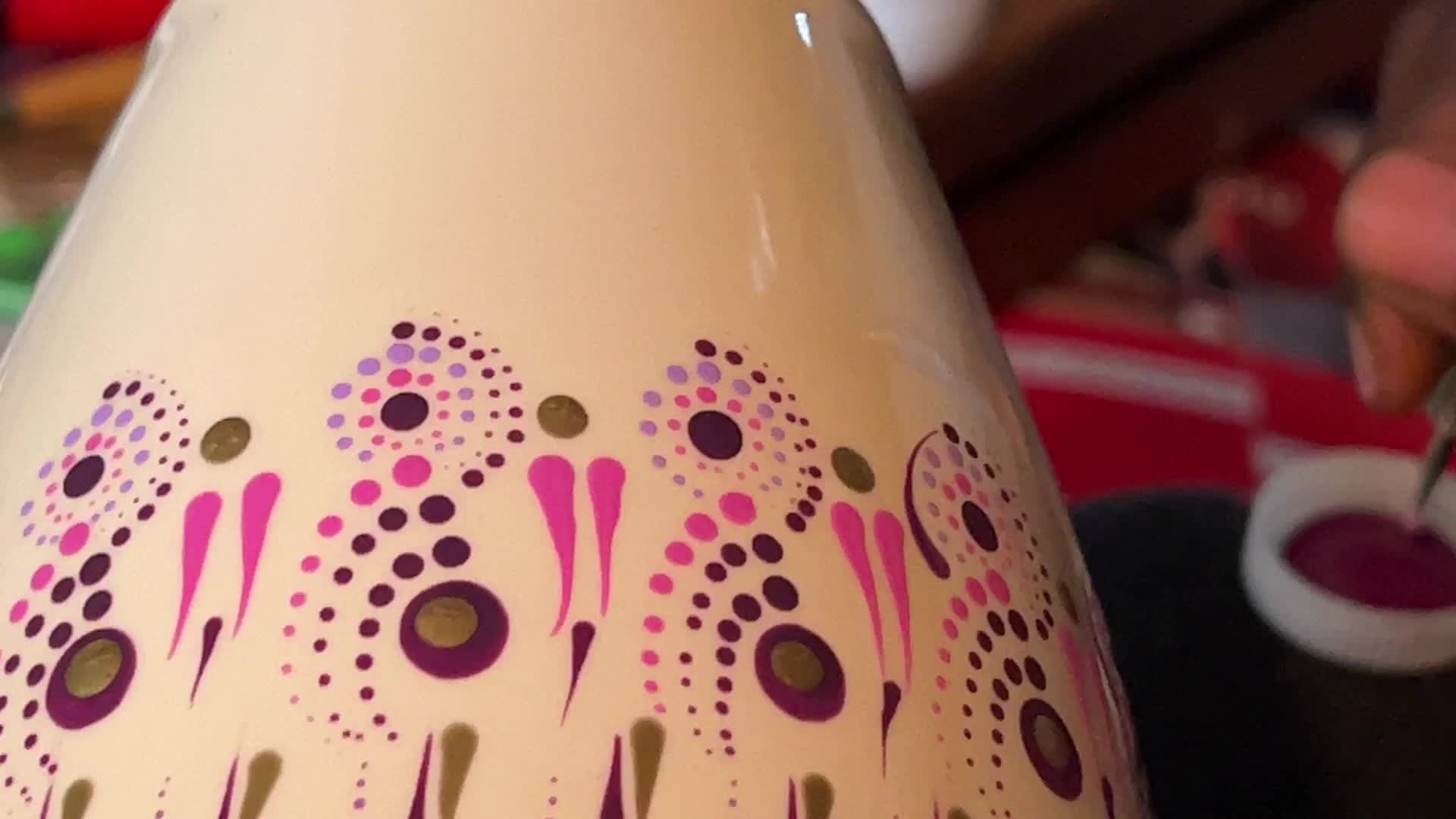 Artist carefully paints a vase with a dot art design
