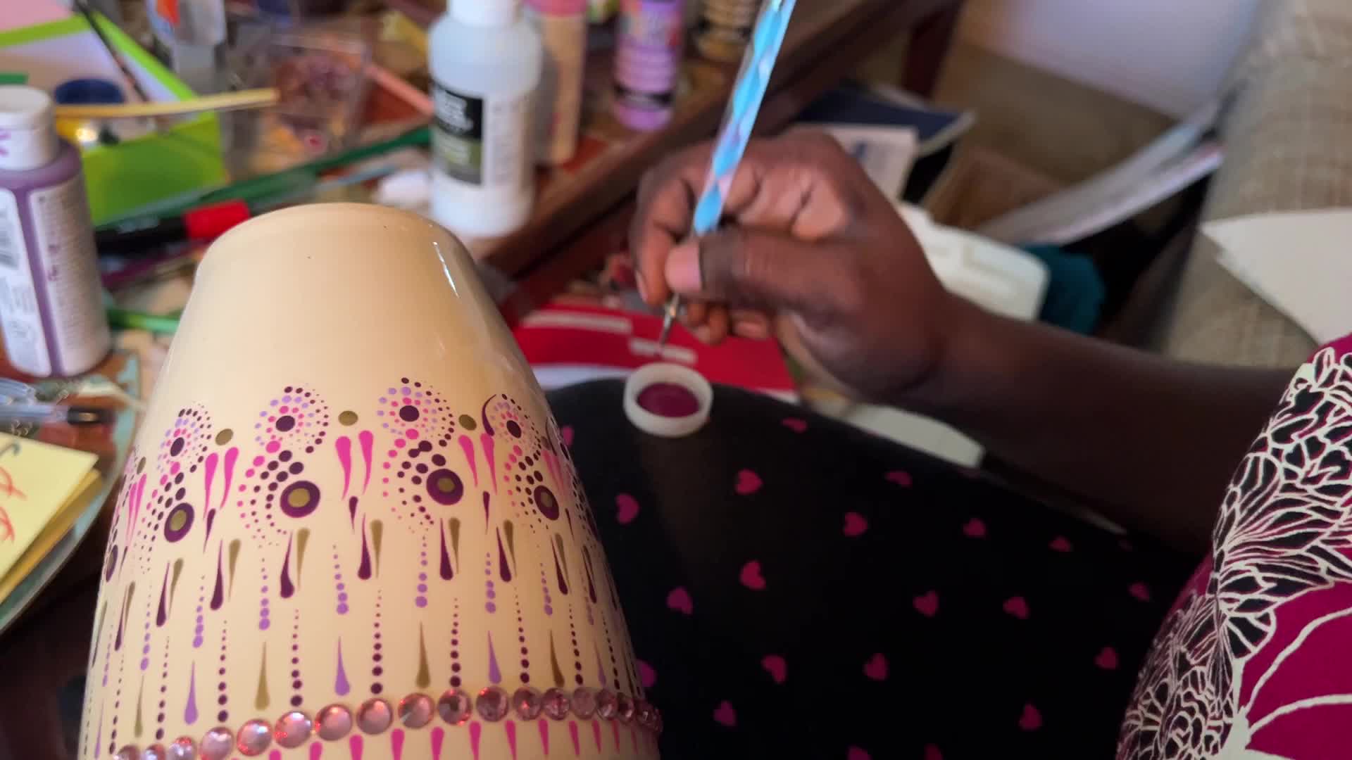 Artist carefully paints a vase with a dot art design
