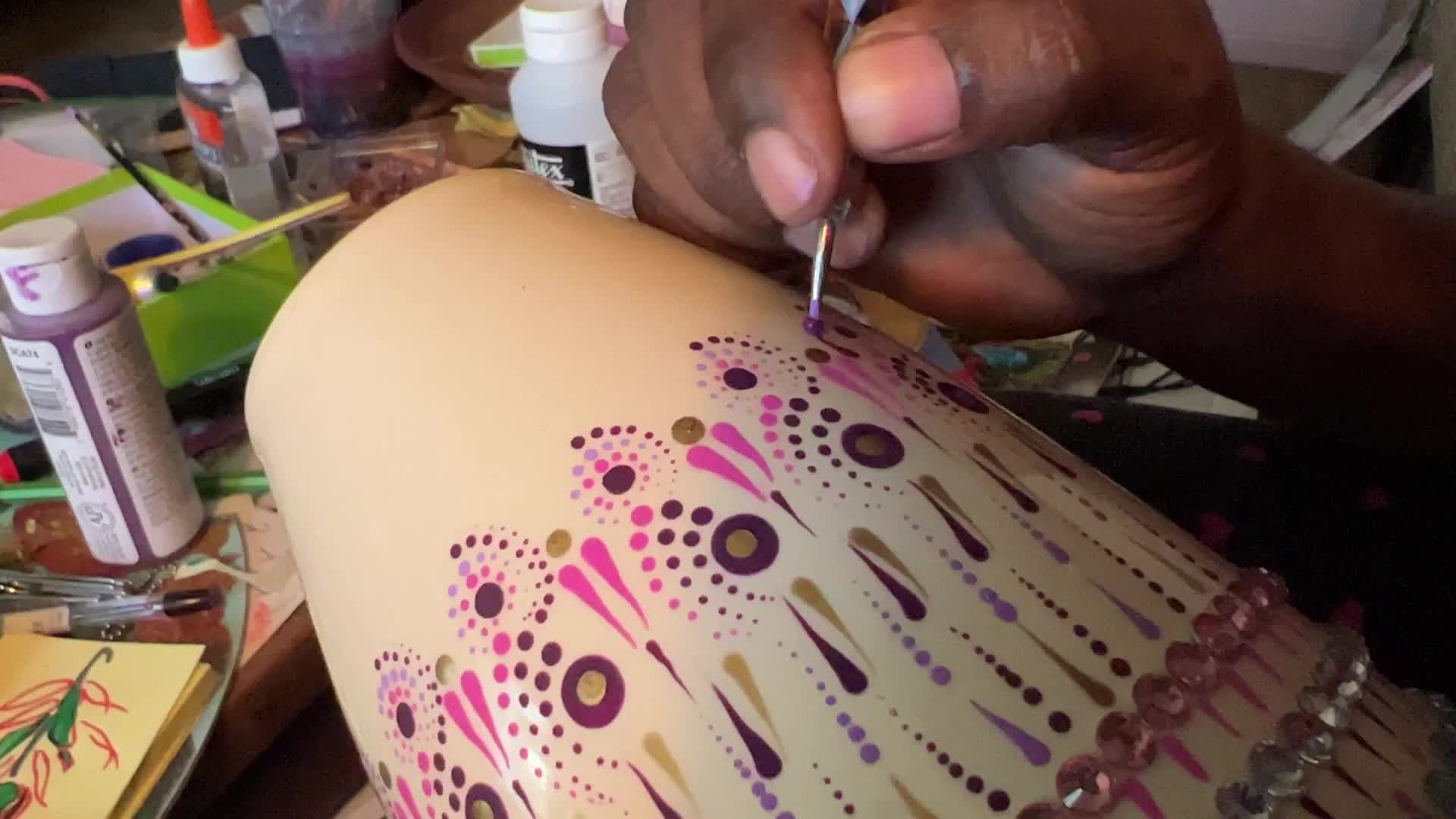 Artist carefully paints a vase with a dot art design
