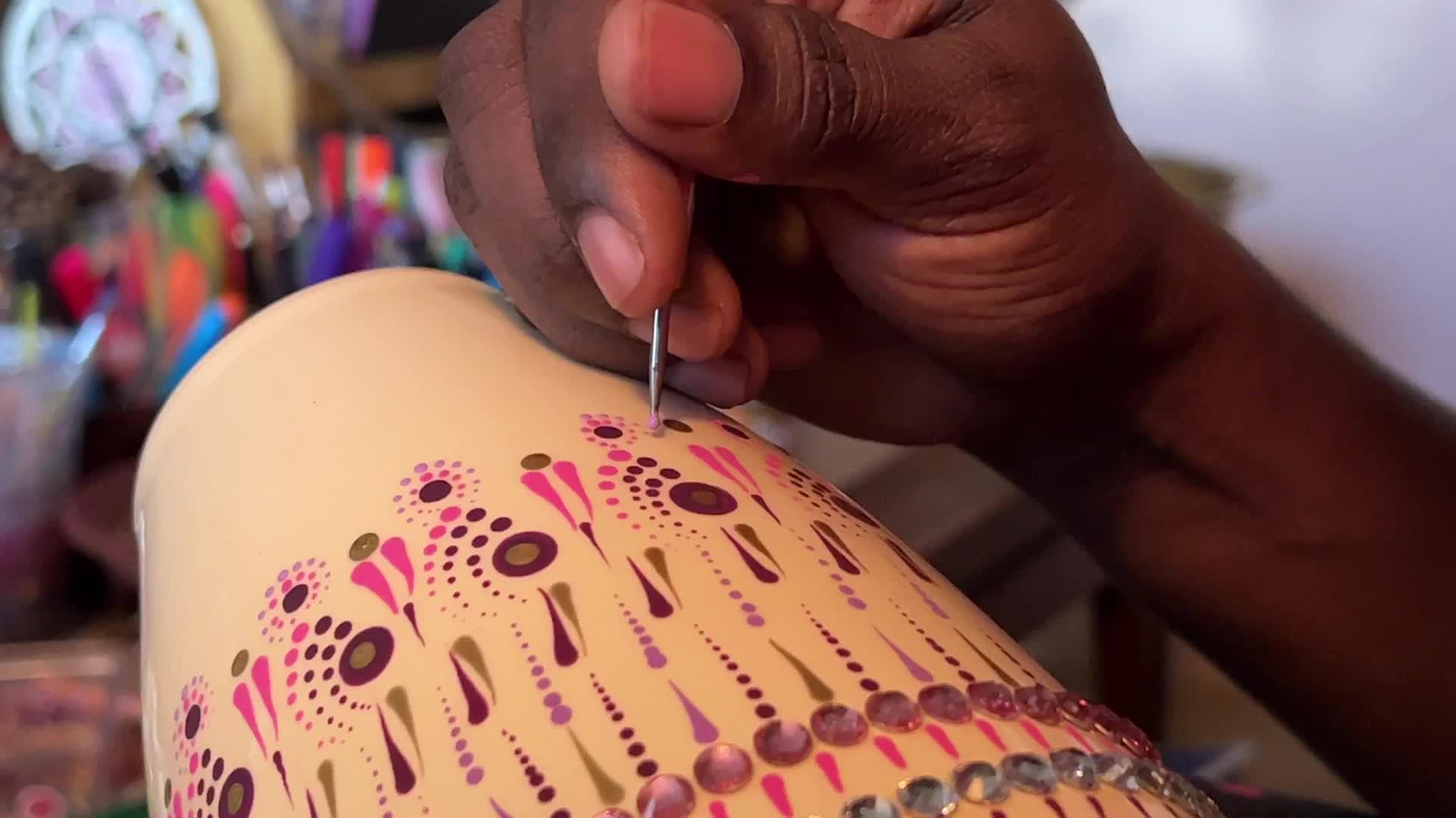 Artist carefully paints a vase with a dot art design