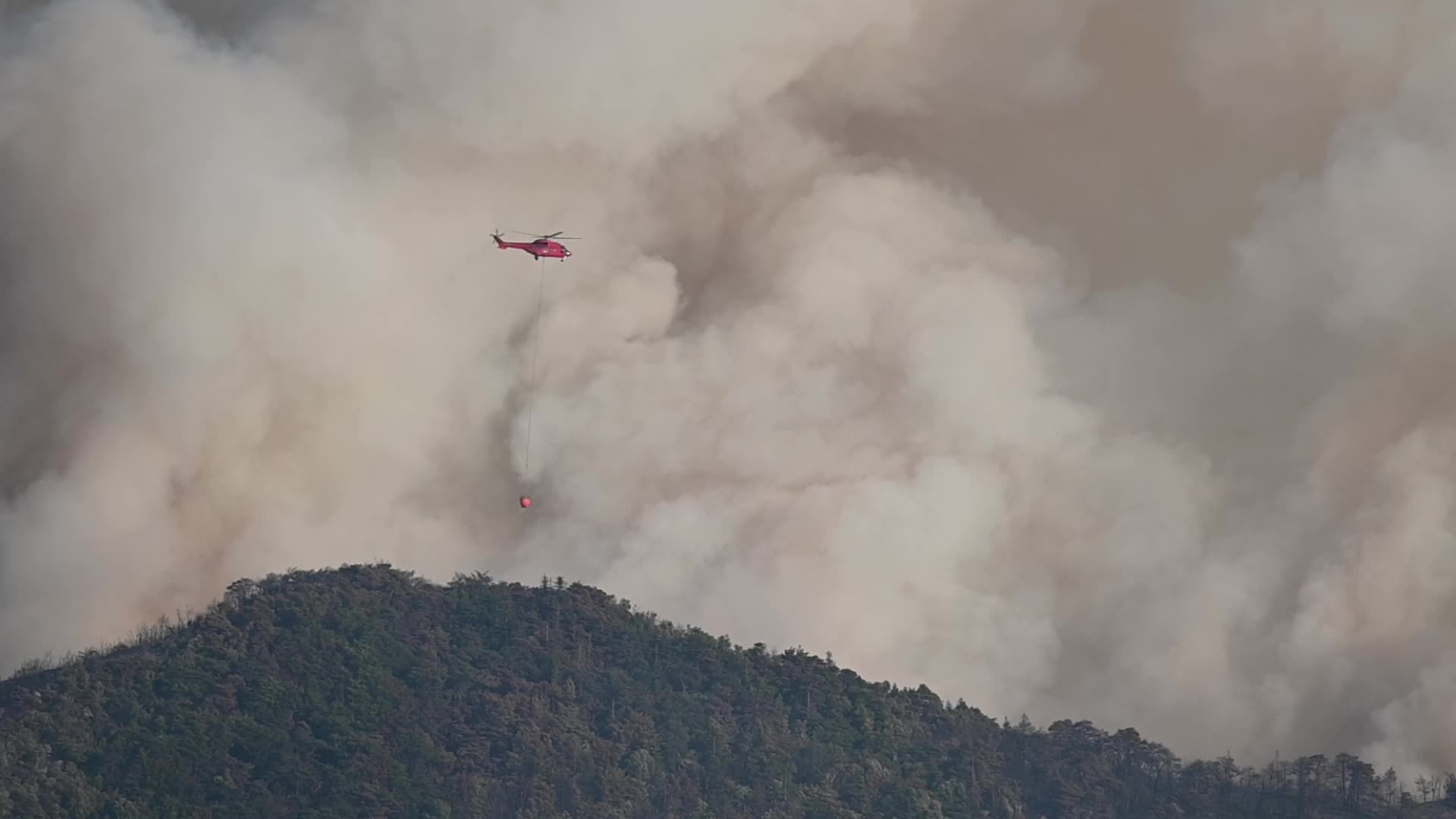 A water bombing helicopter in operation on a major forest fire in the commune of Romeyer
