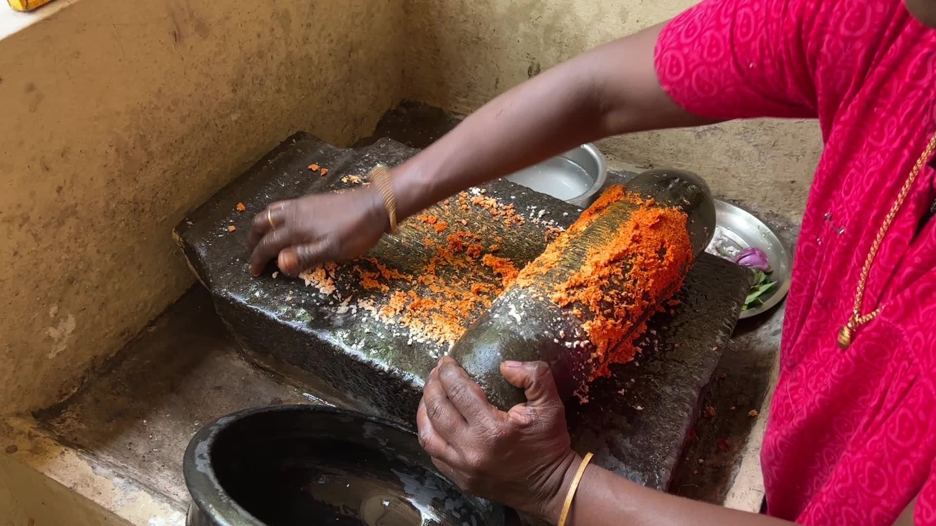 Woman preparing coconut chutney using a traditional roller stone