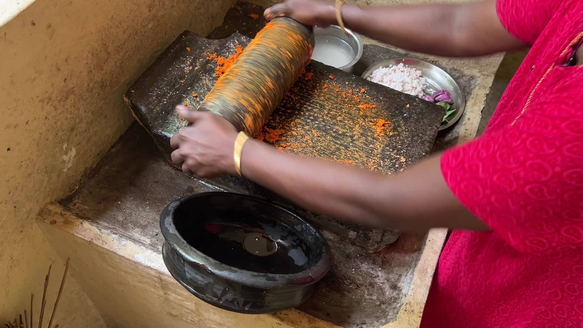 Woman preparing coconut chutney using a traditional roller stone