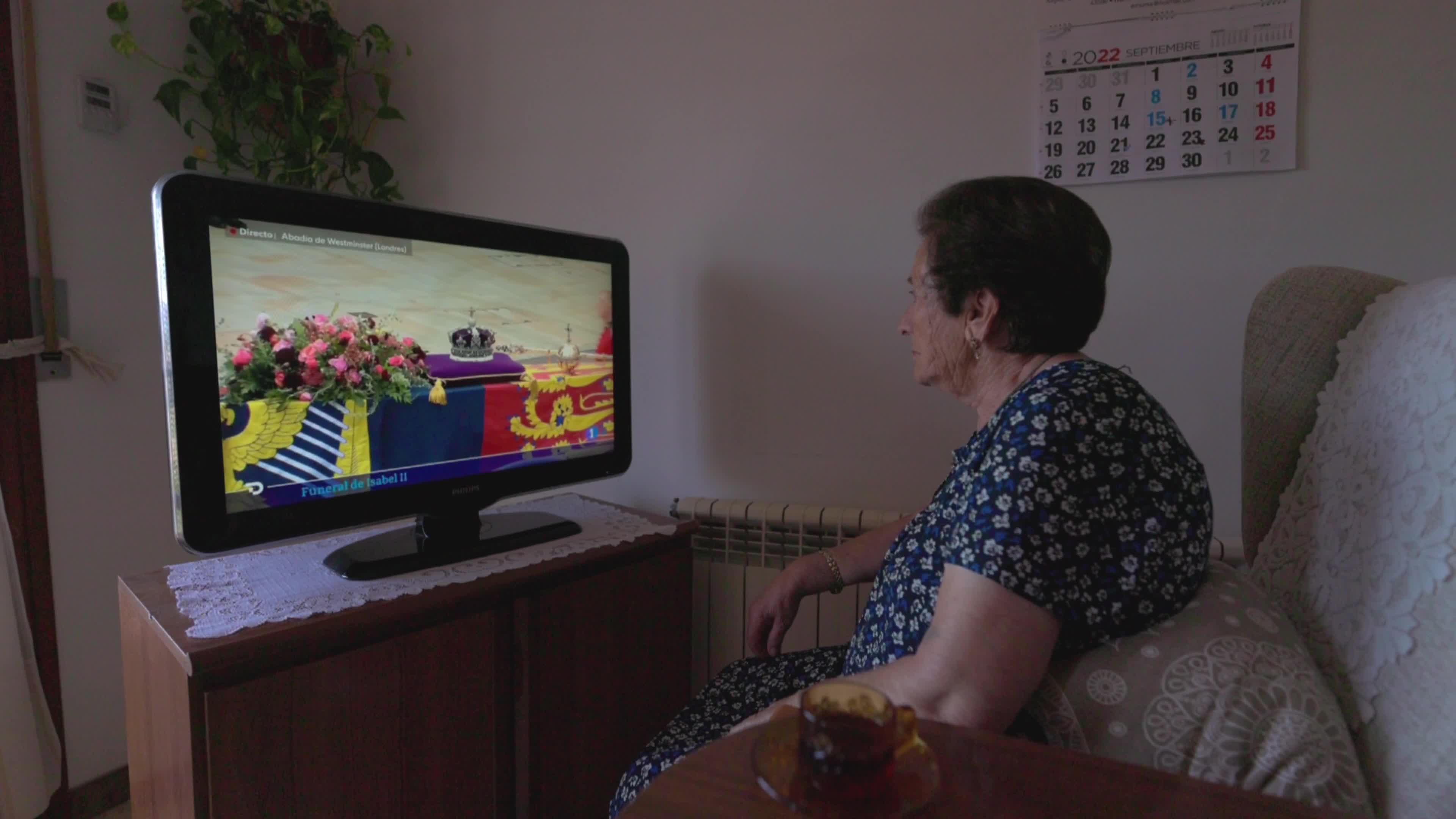 An elderly woman watches Queen Elizabeth II funeral on TV
