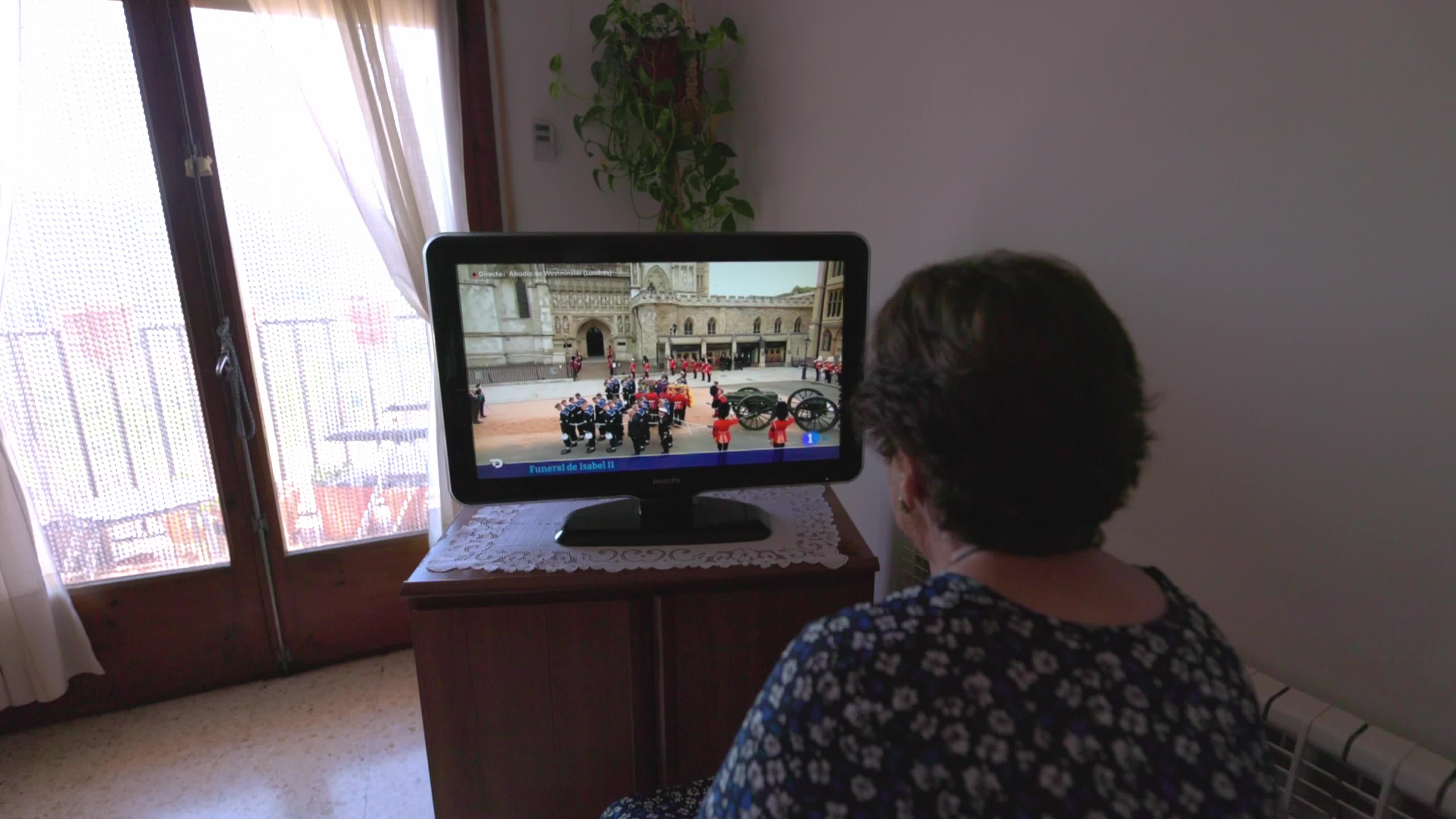 An elderly woman watches Queen Elizabeth II funeral on TV