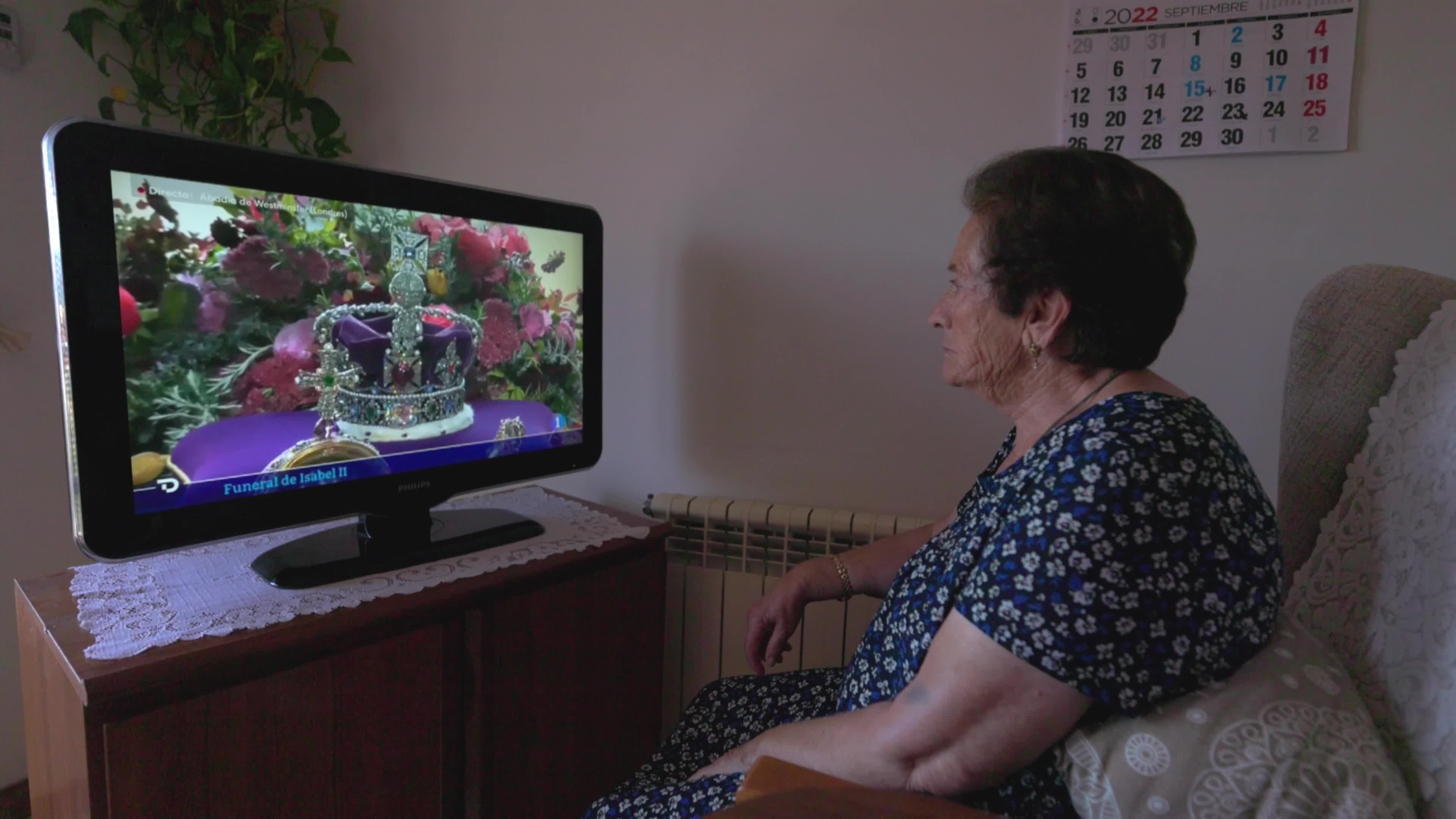 An elderly woman watches Queen Elizabeth II funeral on TV