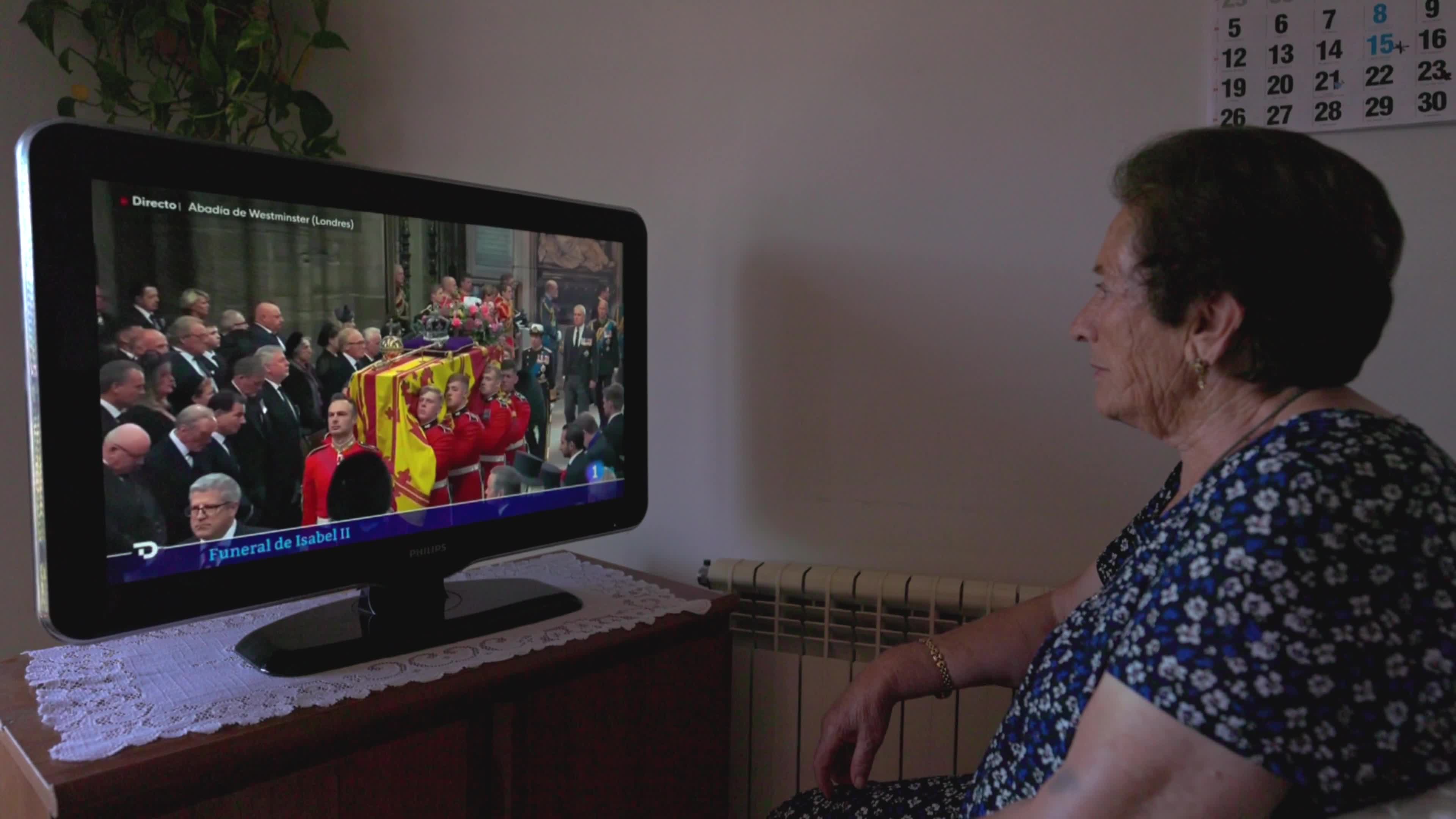 An elderly woman watches Queen Elizabeth II funeral on TV