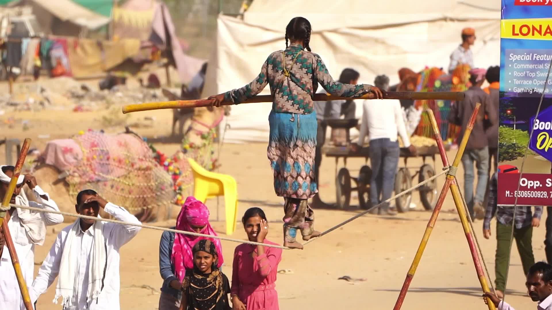 Indian Girl Undertakes a balancing act on a rope during a street show in Pushkar, India