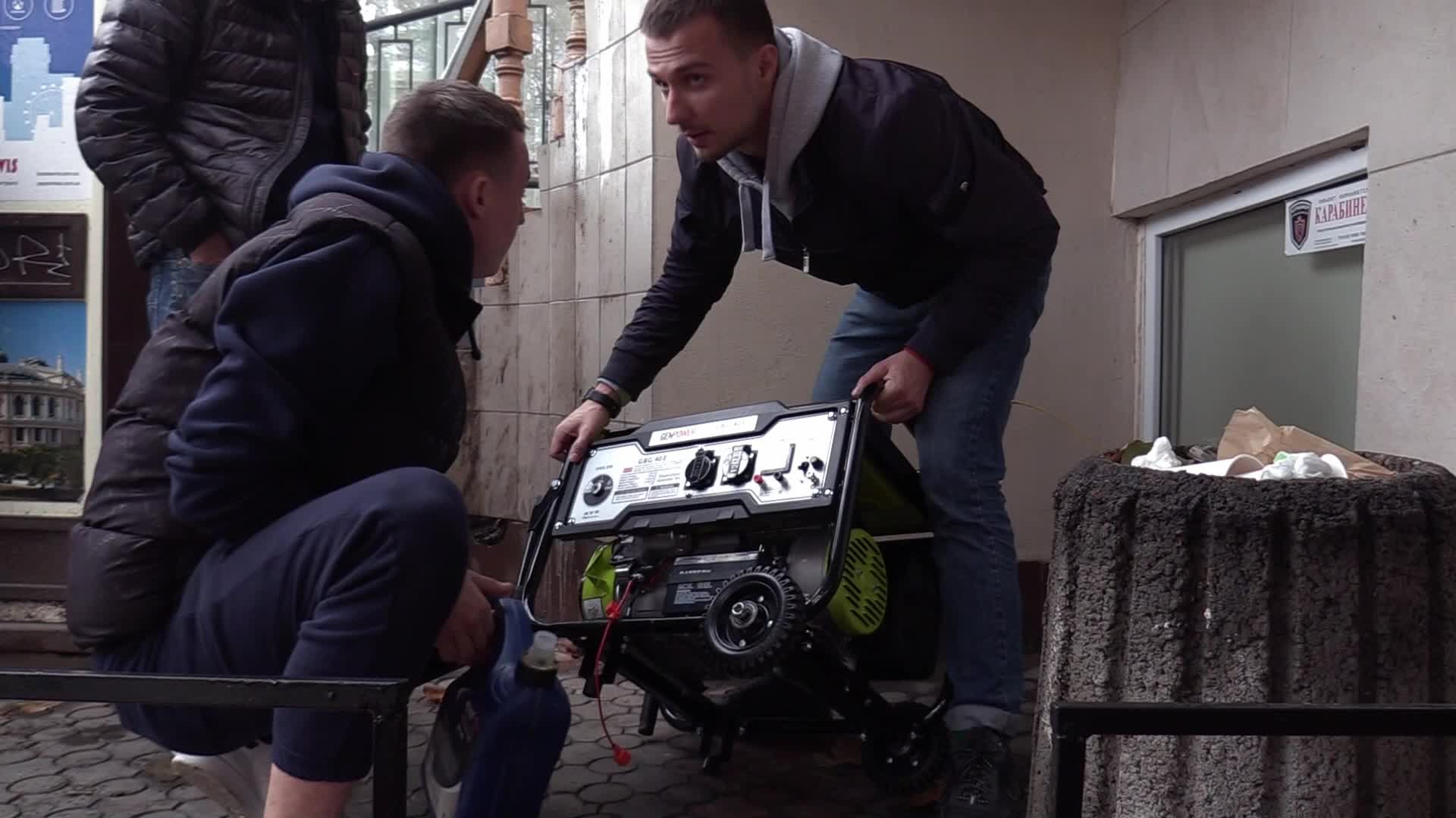 Ukrainians install a electricity generator outside the entrance to a store during emergency power blackout in Odesa