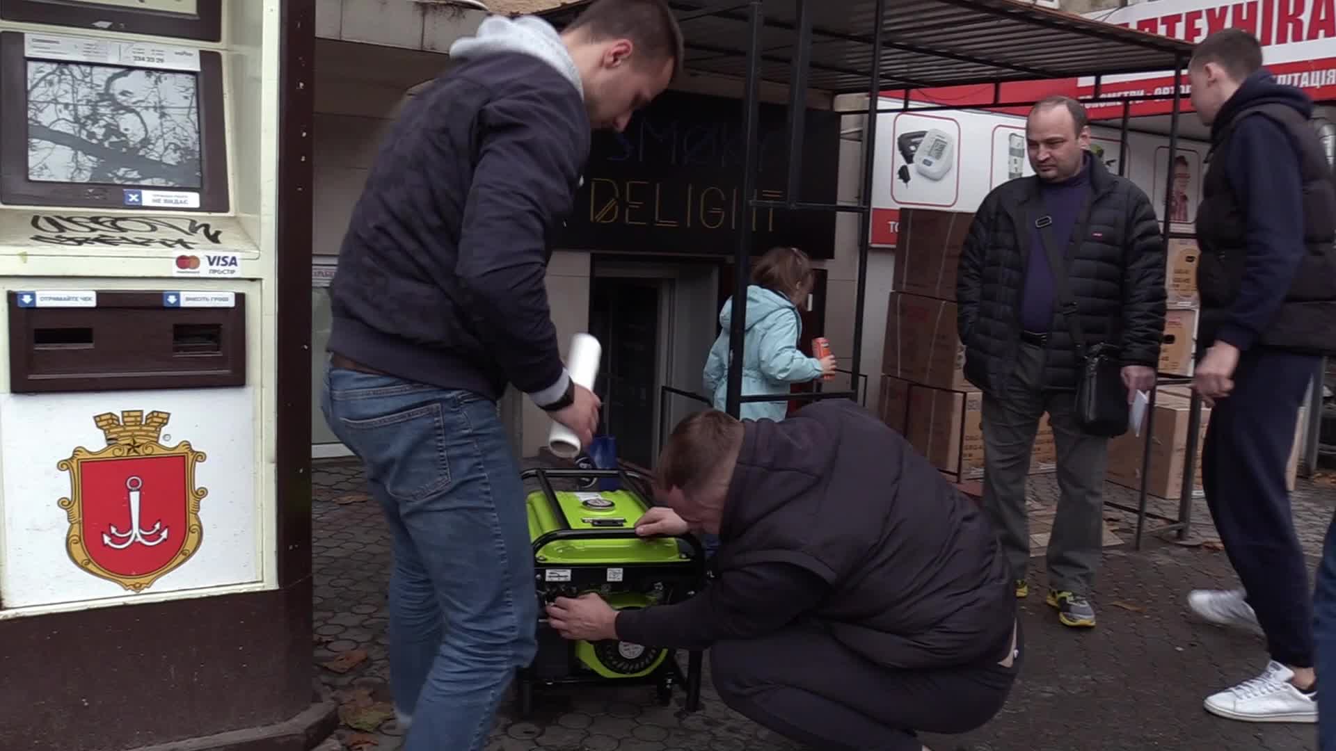 Ukrainians install a electricity generator outside the entrance to a store during emergency power blackout in Odesa