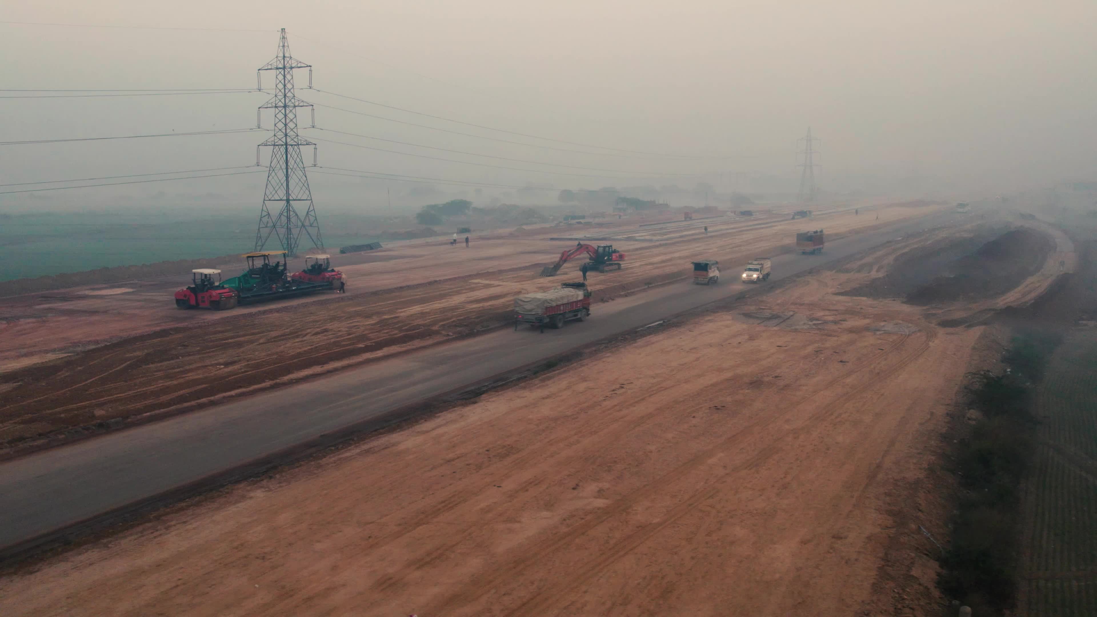 Aerial view of a foggy and misty Morning with Under Construction Highway and moving traffic on the outskirts of New Delhi, India