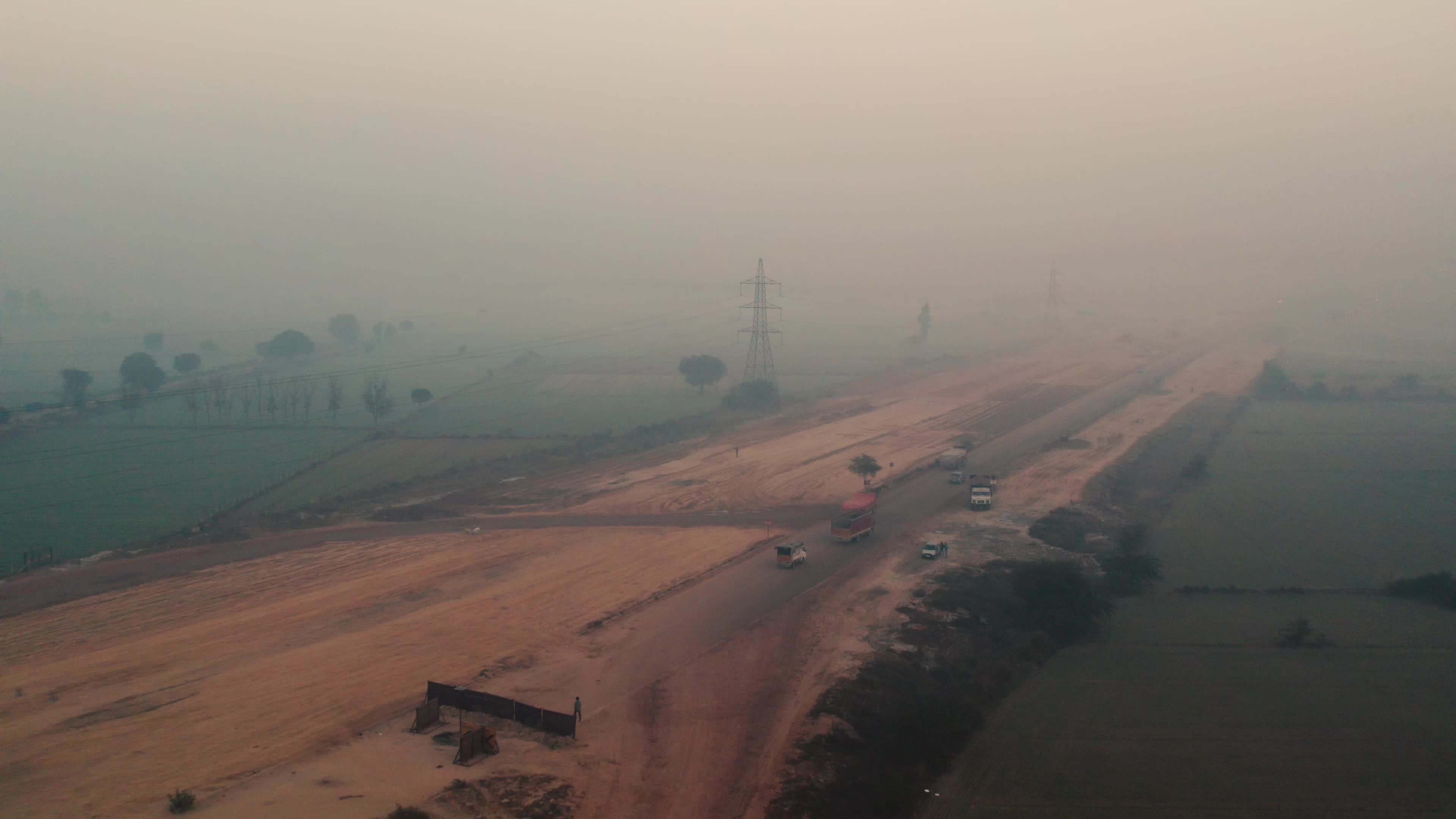 Aerial view of a foggy and misty Morning with Under Construction Highway and moving traffic on the outskirts of New Delhi, India