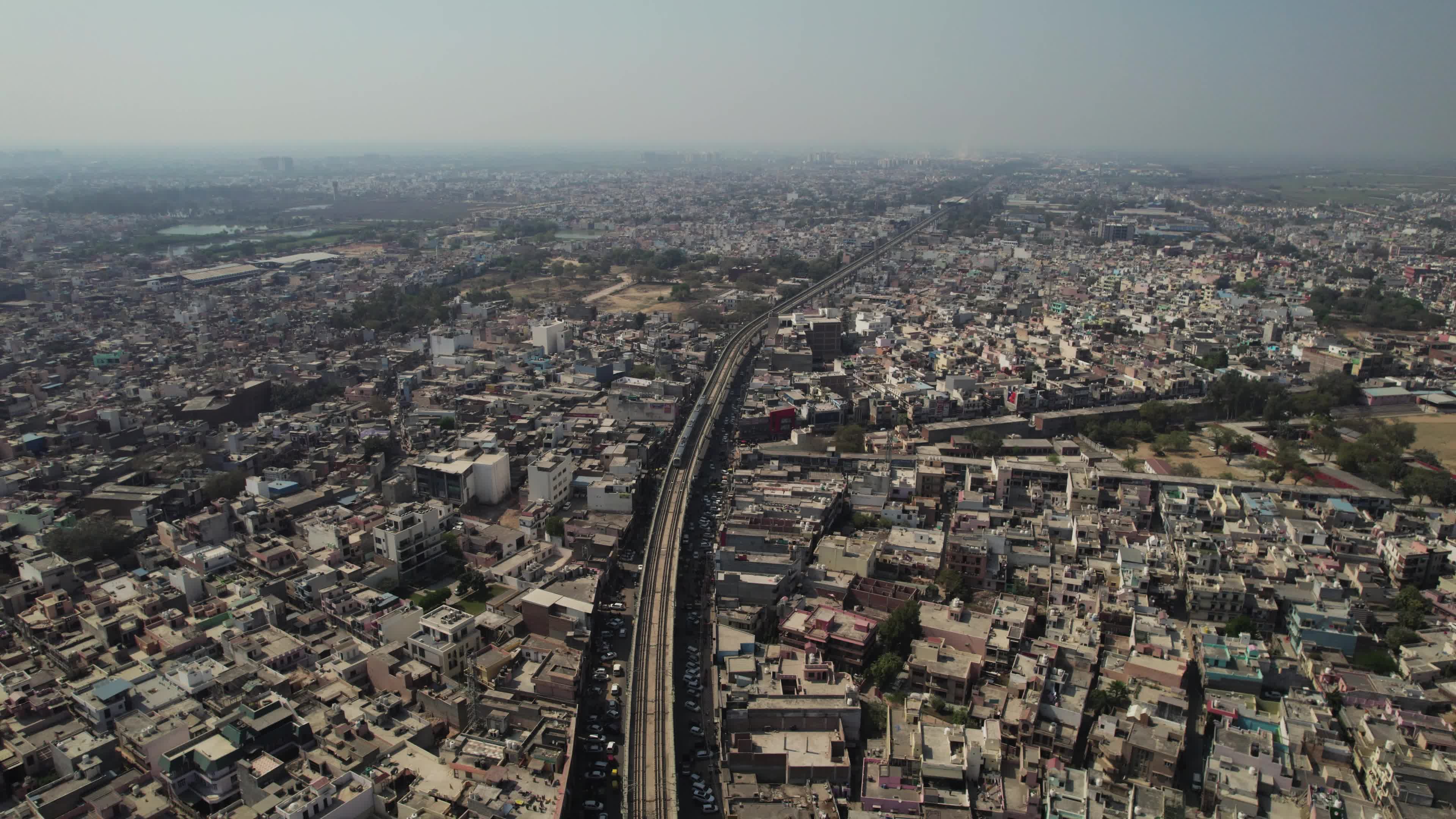 4K Aerial overpopulated View of Industrial & Residential Estate in Bahadurgarh City with elevated Metro train tracks and solar panels installed on the roof of the Metro Station, Harayana, India - stock video