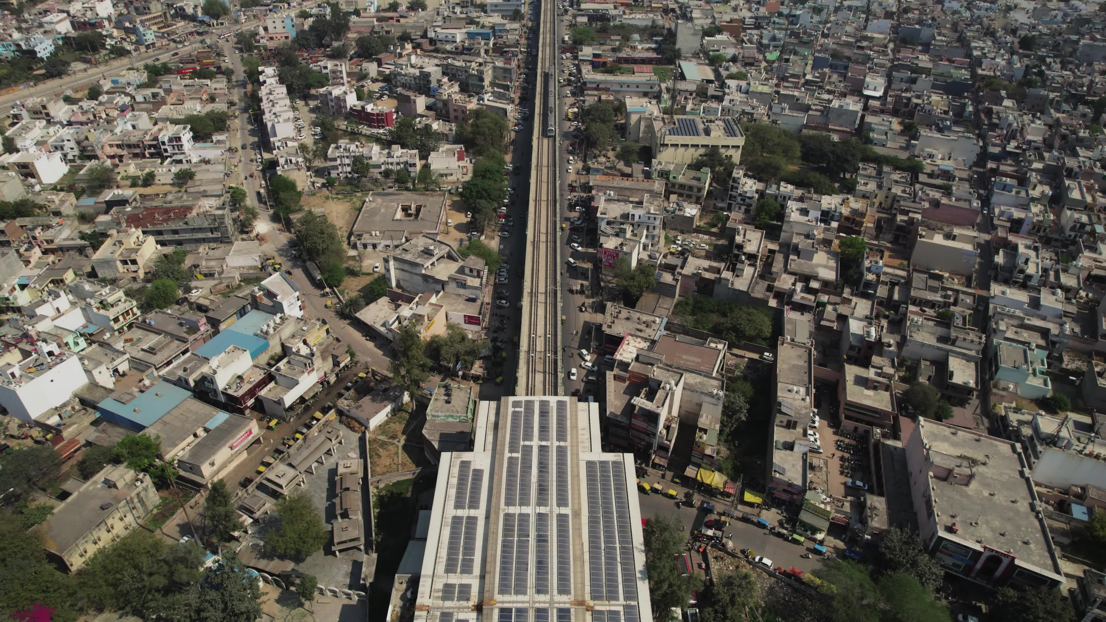 4K Aerial overpopulated View of Industrial & Residential Estate in Bahadurgarh City with elevated Metro train tracks and solar panels installed on the roof of the Metro Station, Harayana, India - stock video