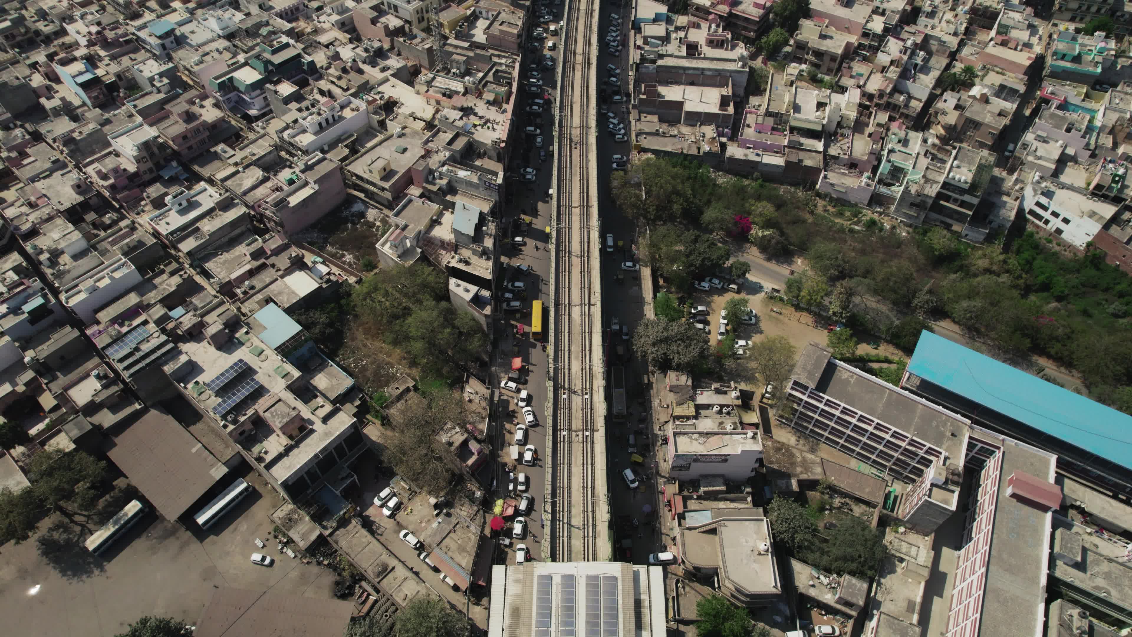 4K Aerial overpopulated View of Industrial & Residential Estate in Bahadurgarh City with elevated Metro train tracks and solar panels installed on the roof of the Metro Station, Harayana, India - stock video