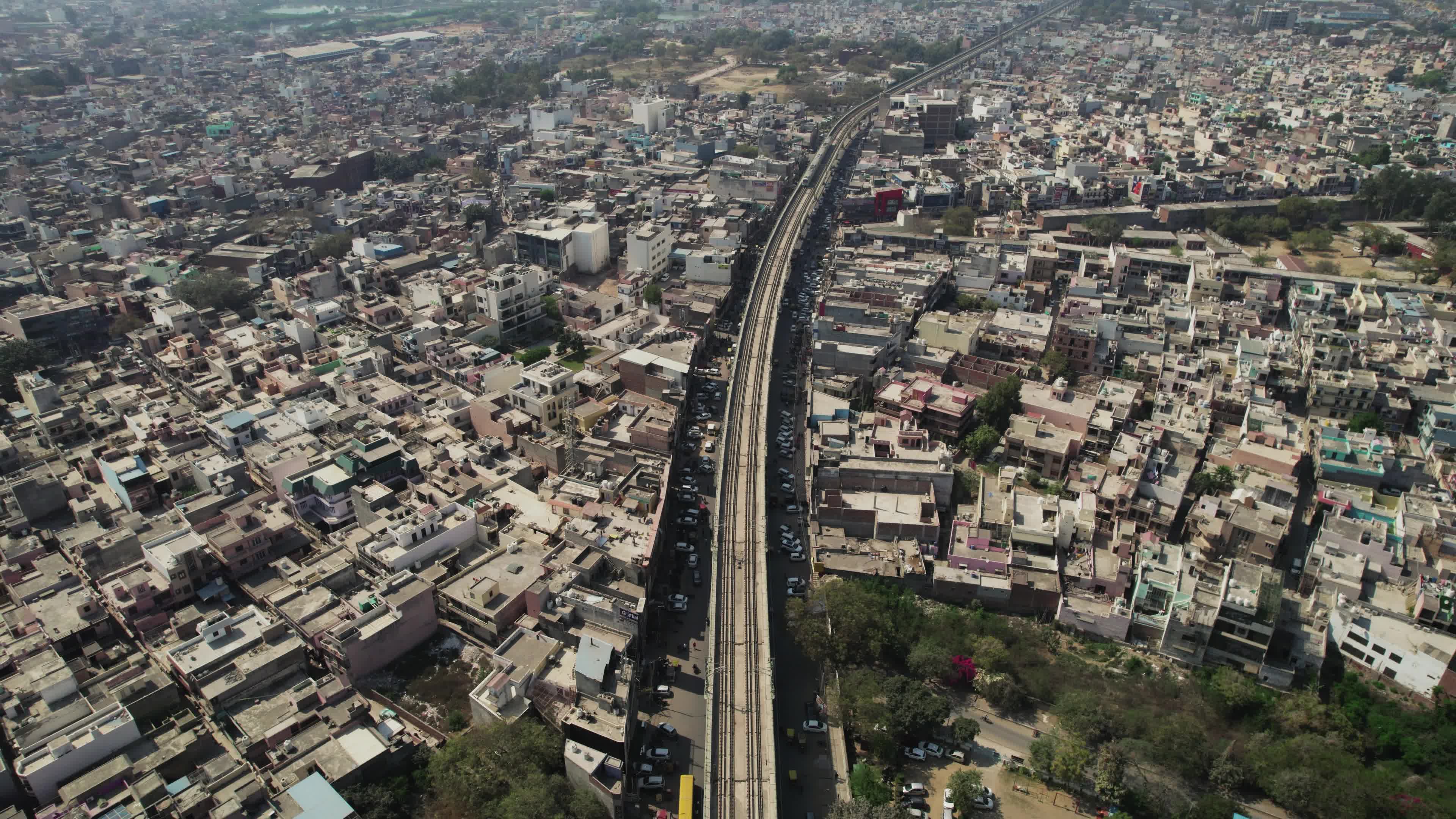 4K Aerial overpopulated View of Industrial & Residential Estate in Bahadurgarh City with elevated Metro train tracks and solar panels installed on the roof of the Metro Station, Harayana, India - stock video