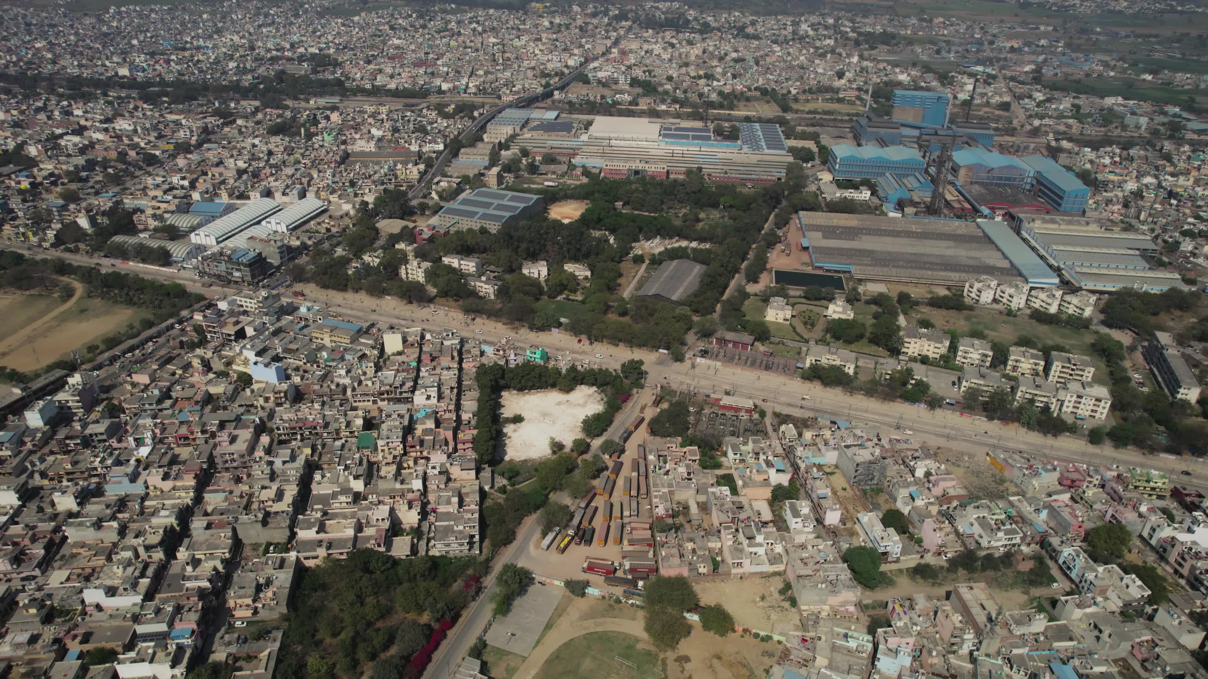 4K Aerial overpopulated View of Industrial & Residential Estate in Bahadurgarh City with elevated Metro train tracks and solar panels installed on the roof of the Metro Station, Harayana, India - stock video