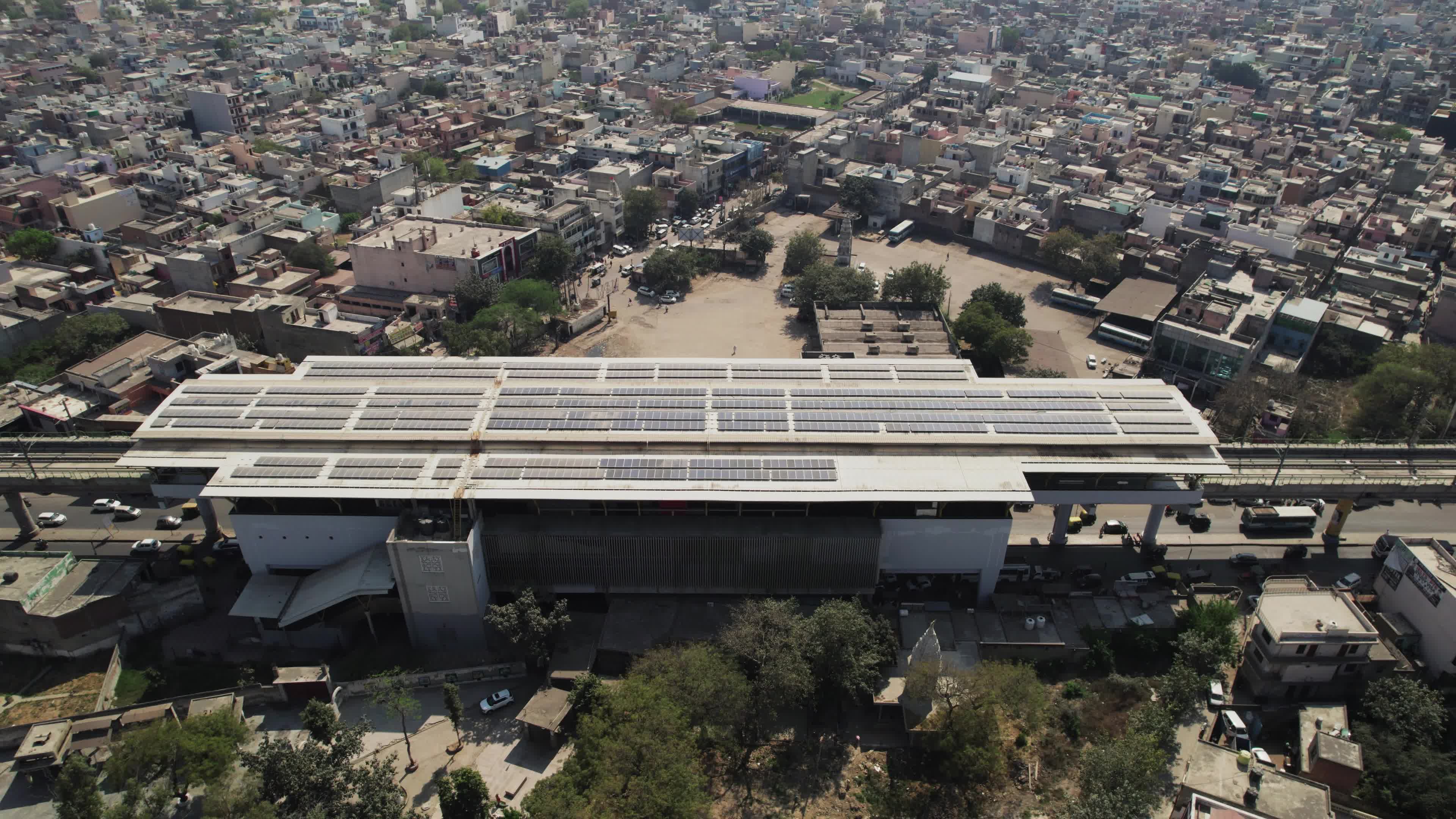 4K Aerial overpopulated View of Industrial & Residential Estate in Bahadurgarh City with elevated Metro train tracks and solar panels installed on the roof of the Metro Station, Harayana, India - stock video