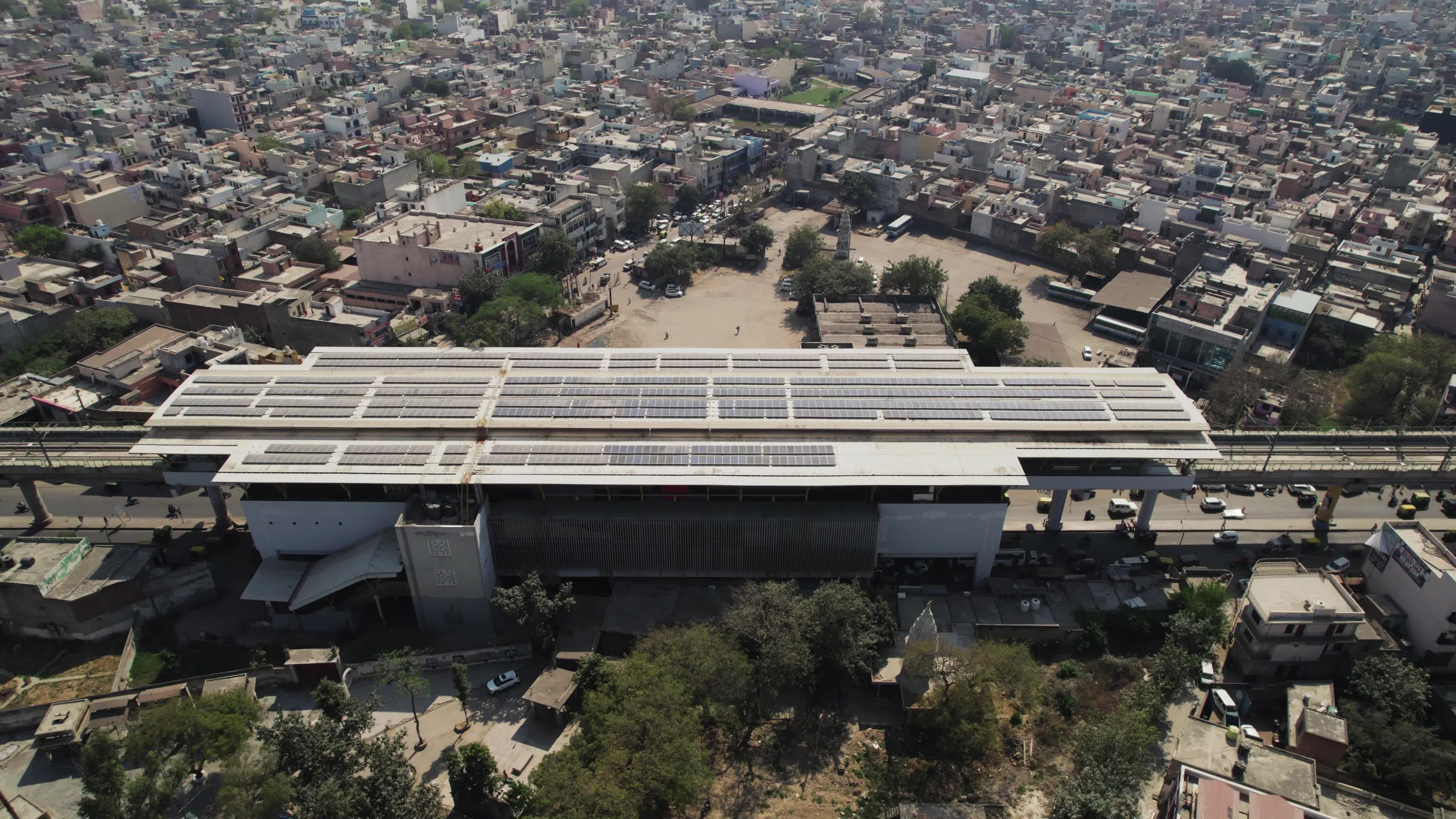 4K Aerial overpopulated View of Industrial & Residential Estate in Bahadurgarh City with elevated Metro train tracks and solar panels installed on the roof of the Metro Station, Harayana, India - stock video