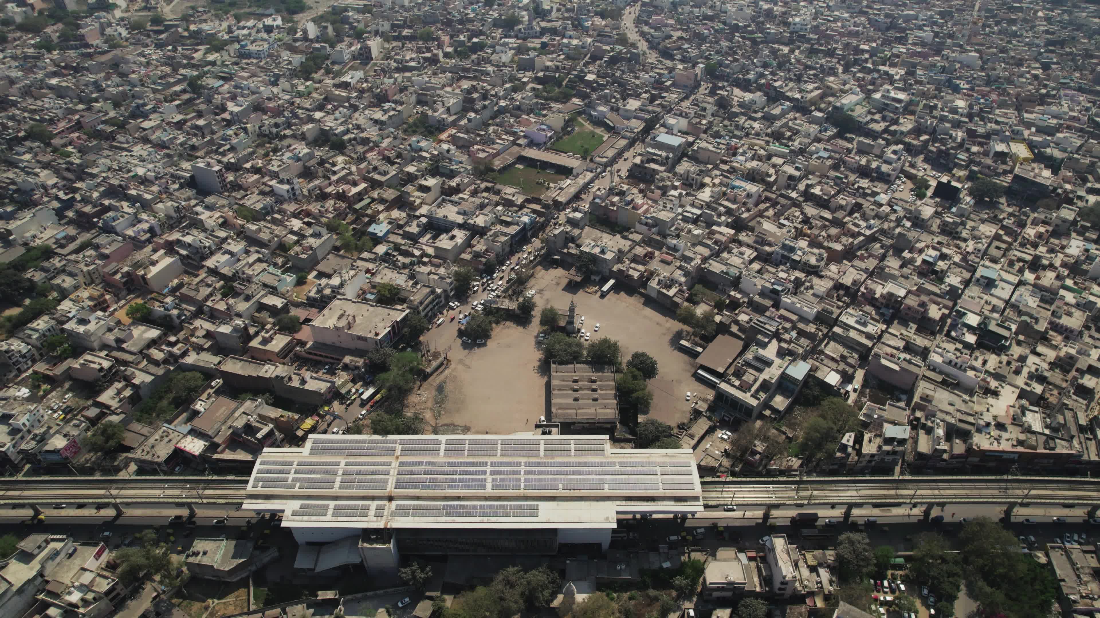 4K Aerial overpopulated View of Industrial & Residential Estate in Bahadurgarh City with elevated Metro train tracks and solar panels installed on the roof of the Metro Station, Harayana, India - stock video