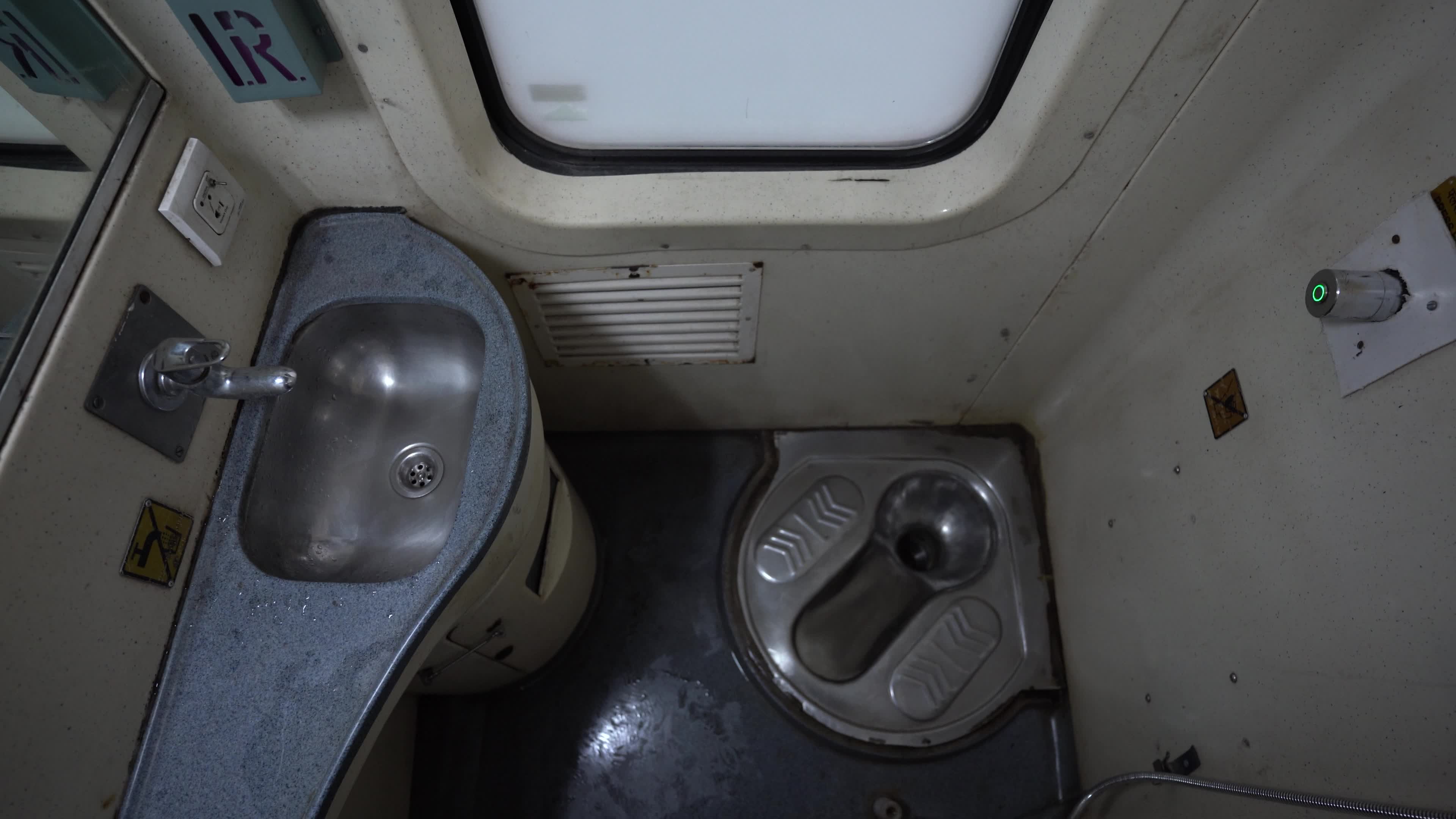 An Indian seat toilet and wash basin in a passenger train of Indian Railways in India, in a moving train