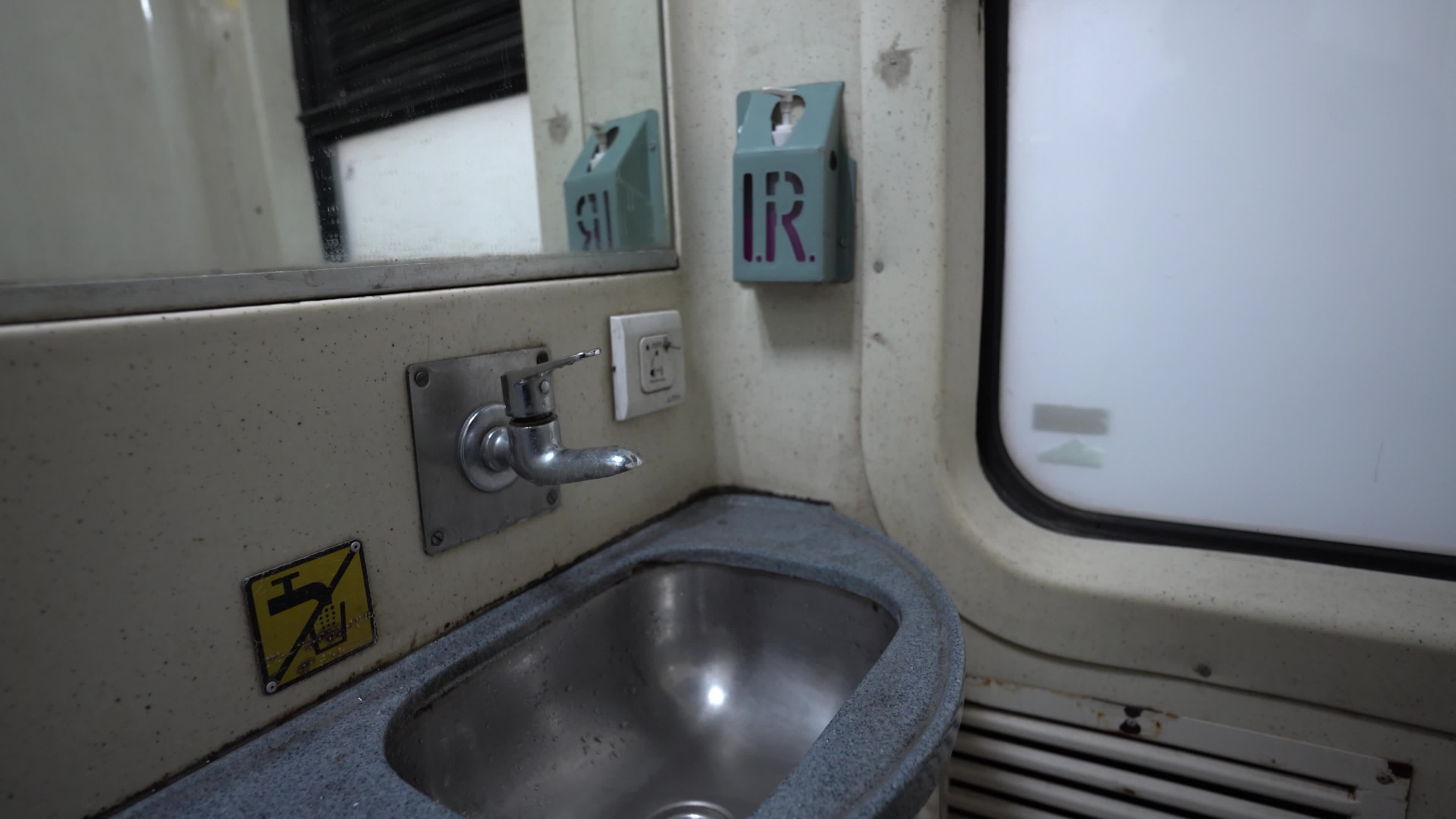 An Indian style metal wash basin in a passenger train of Indian Railways in India, in a moving train