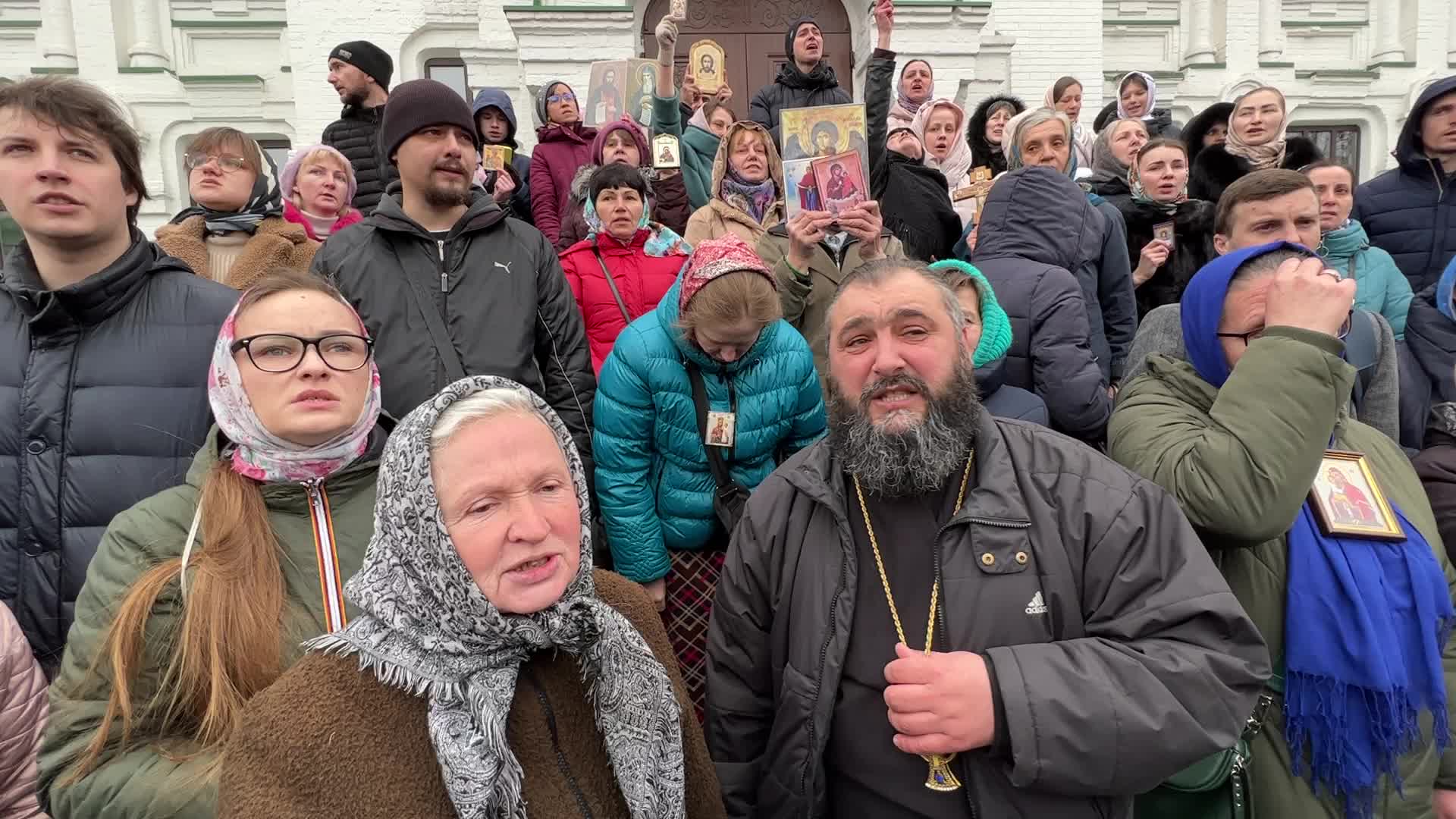 Priests and believers of the Ukrainian Orthodox Church of the Moscow Patriarchate pray while they block an entrance to a church 