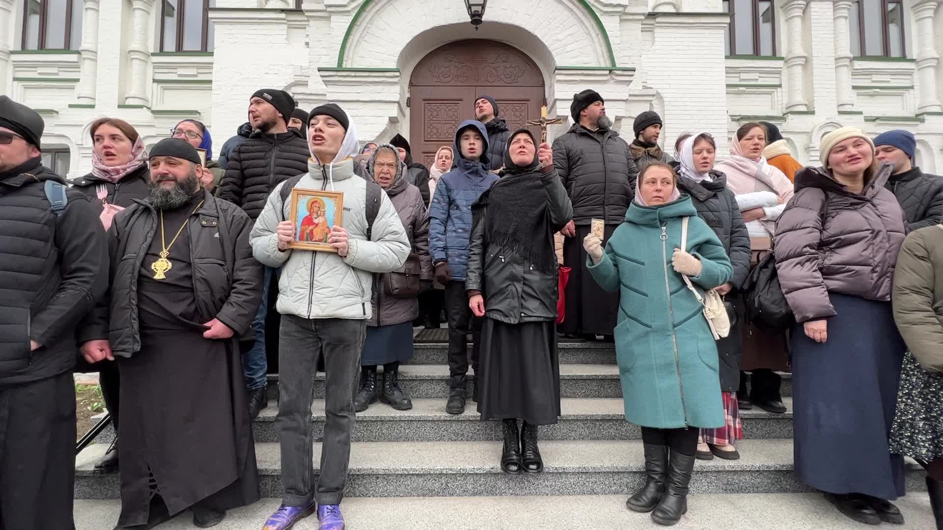 Priests and believers of the Ukrainian Orthodox Church of the Moscow Patriarchate pray while they block an entrance to a church 