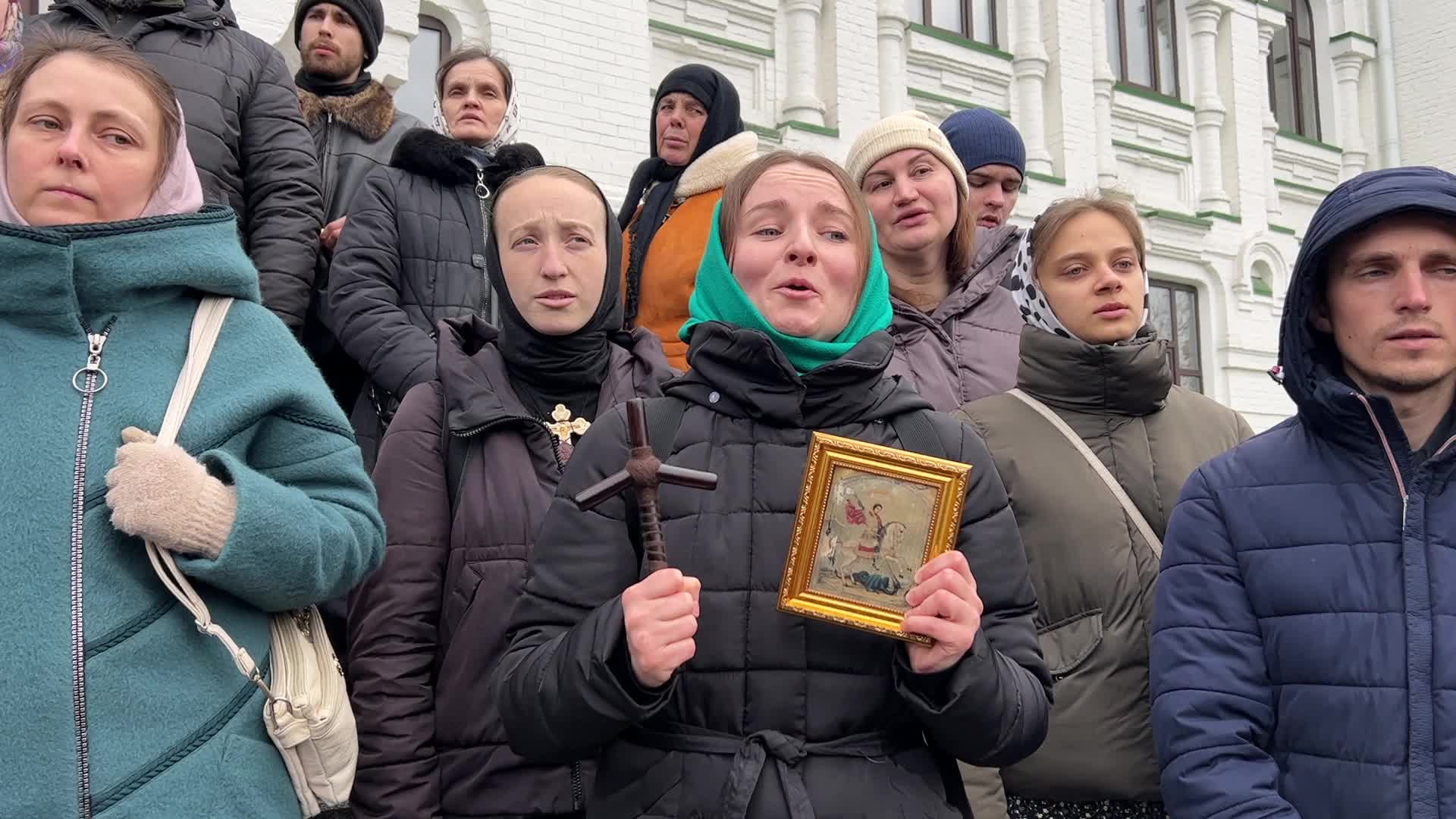 Priests and believers of the Ukrainian Orthodox Church of the Moscow Patriarchate pray while they block an entrance to a church 