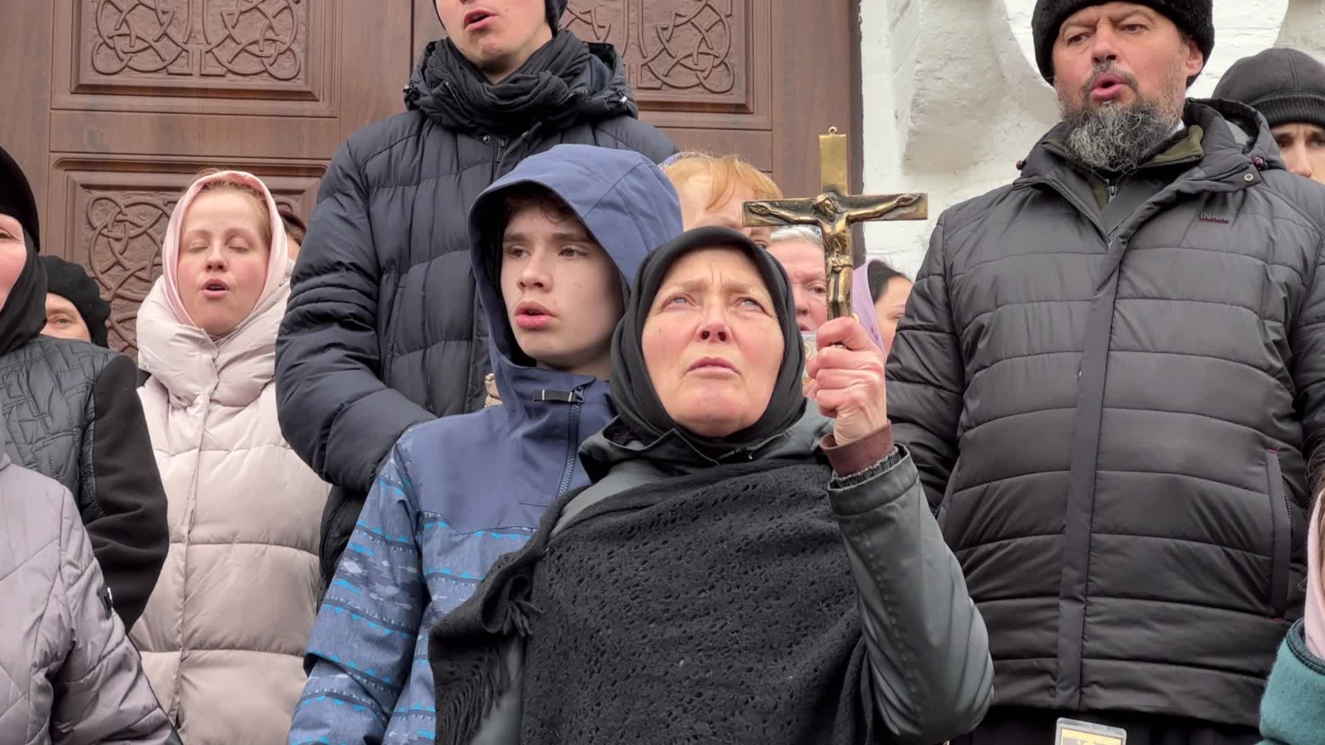 Priests and believers of the Ukrainian Orthodox Church of the Moscow Patriarchate pray while they block an entrance to a church 