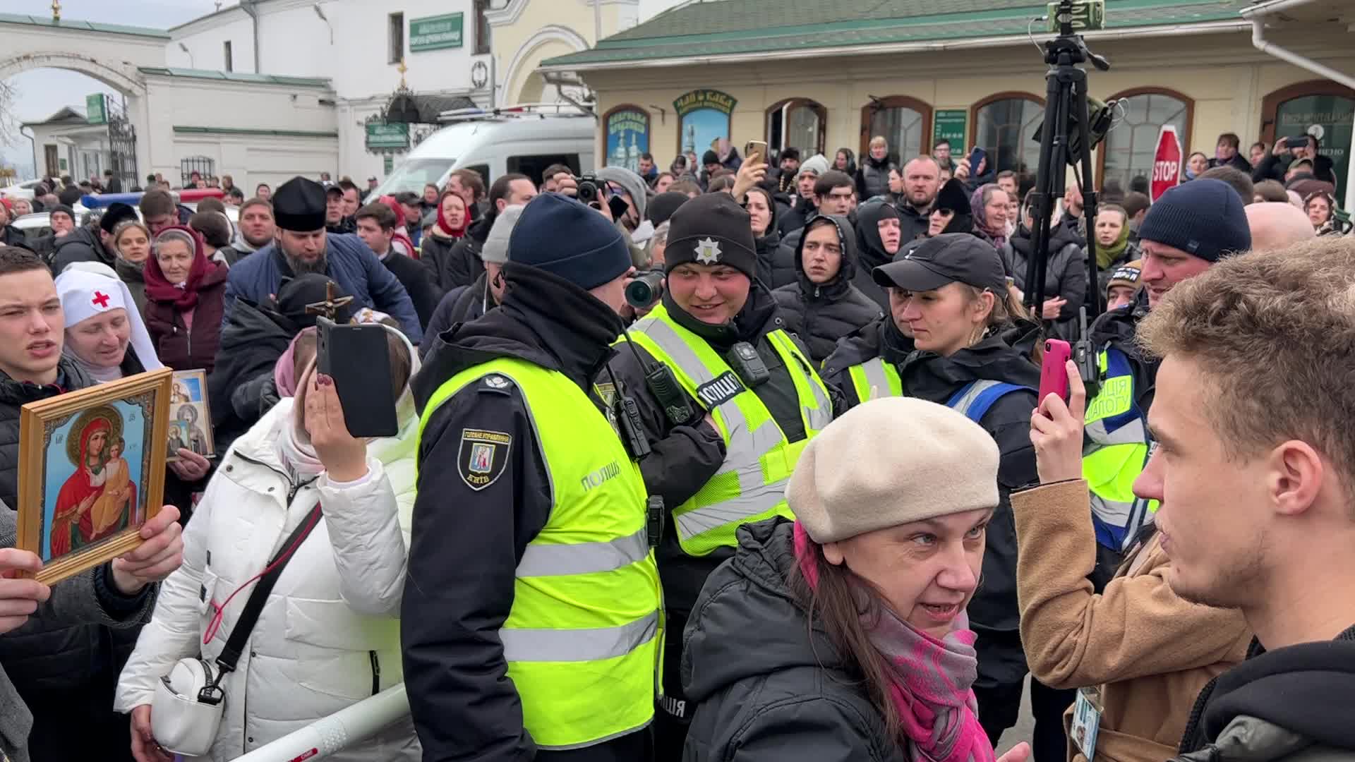 Priests and believers of the Ukrainian Orthodox Church of the Moscow Patriarchate pray while they block an entrance to a church 
