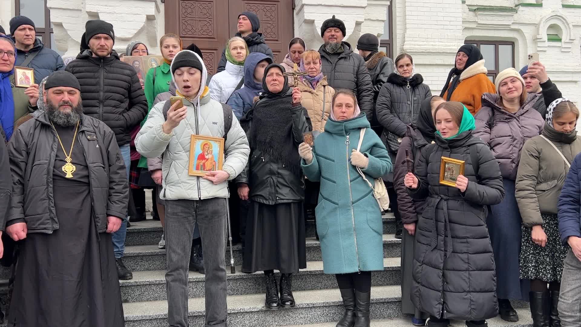 Priests and believers of the Ukrainian Orthodox Church of the Moscow Patriarchate pray while they block an entrance to a church 