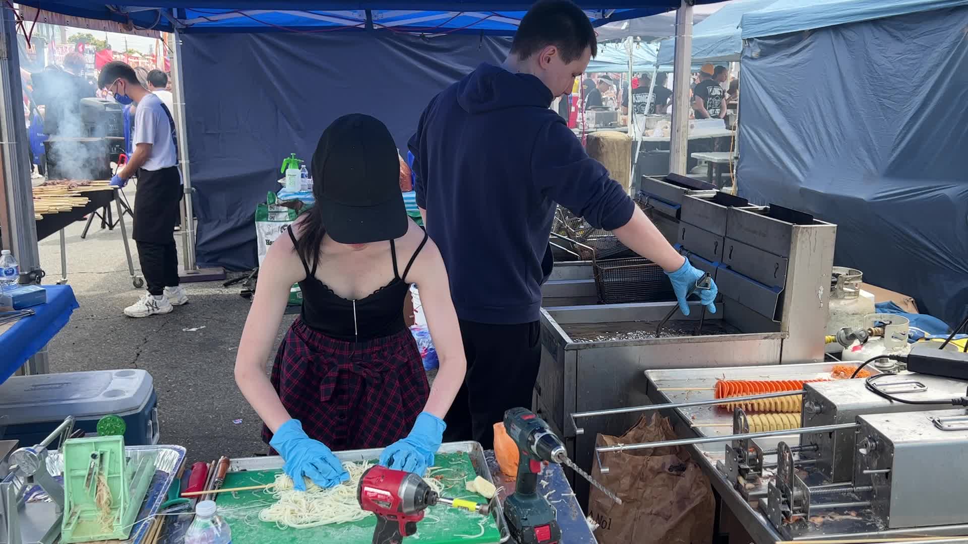 People prepare tornado potatoes during the Taste of Asia Food Festival