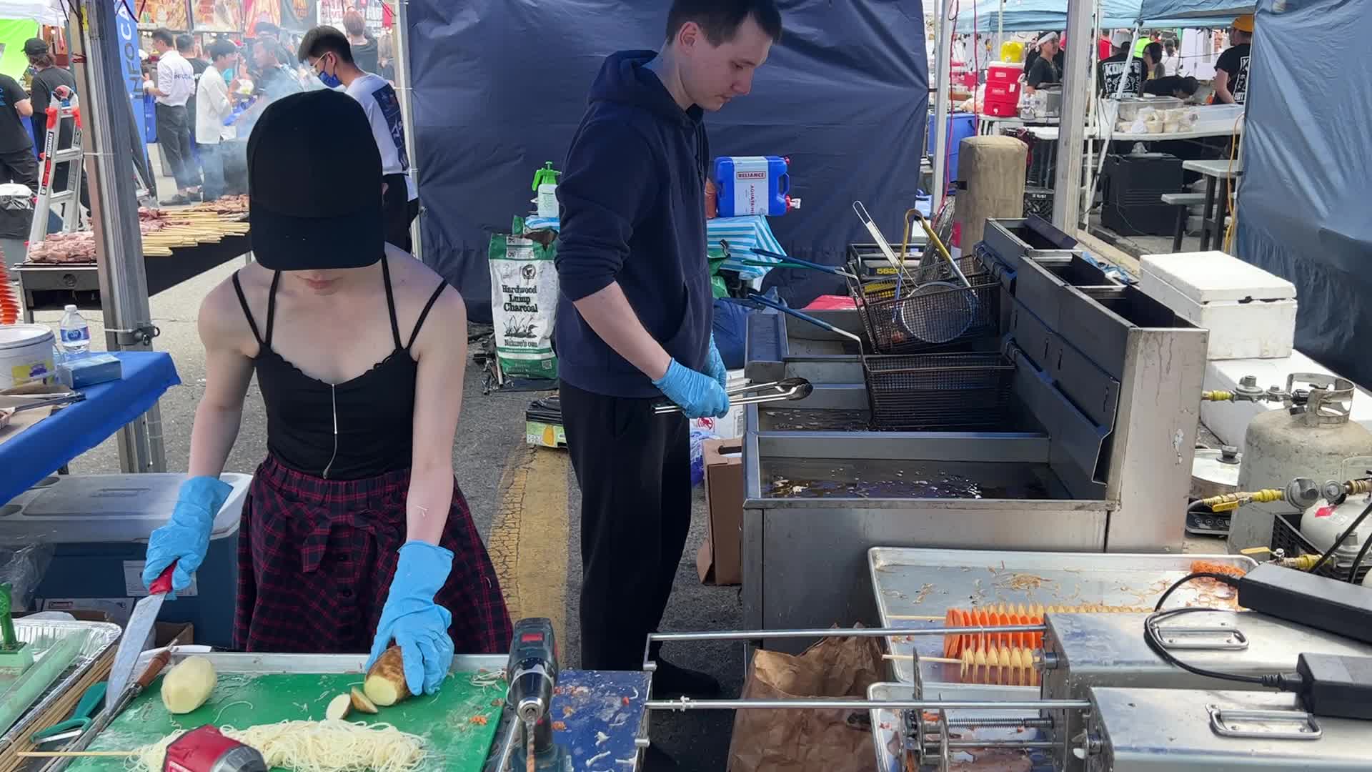 People prepare tornado potatoes during the Taste of Asia Food Festival