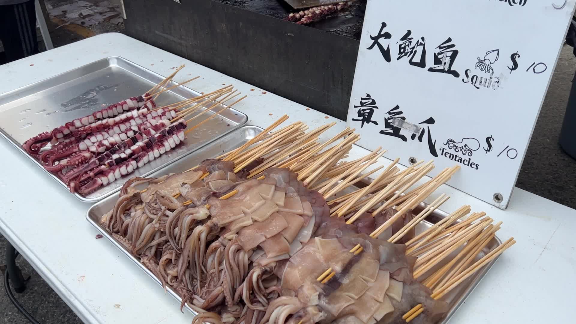 Man grills skewers of octopus tentacles