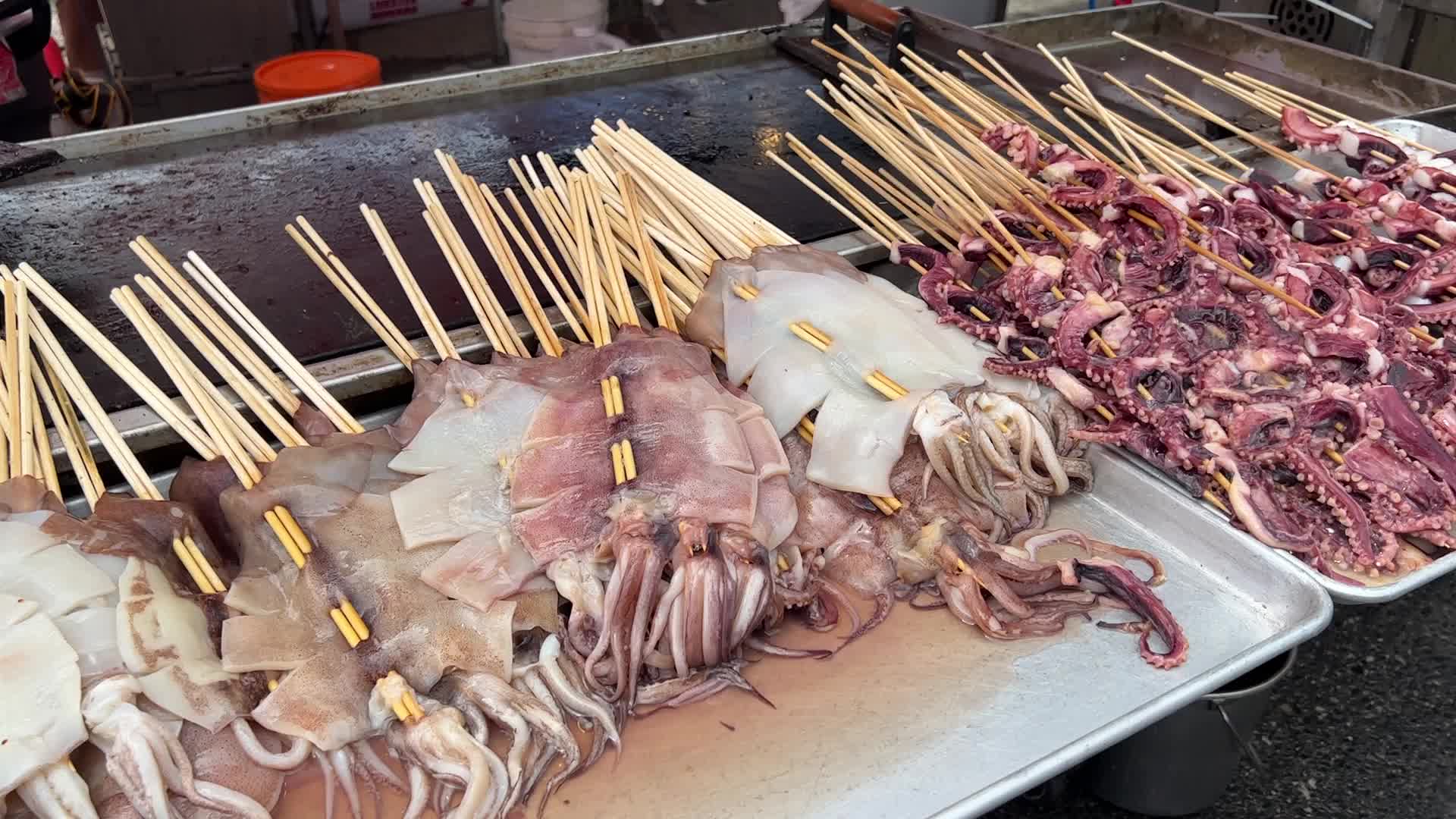 Man grills skewers of octopus tentacles