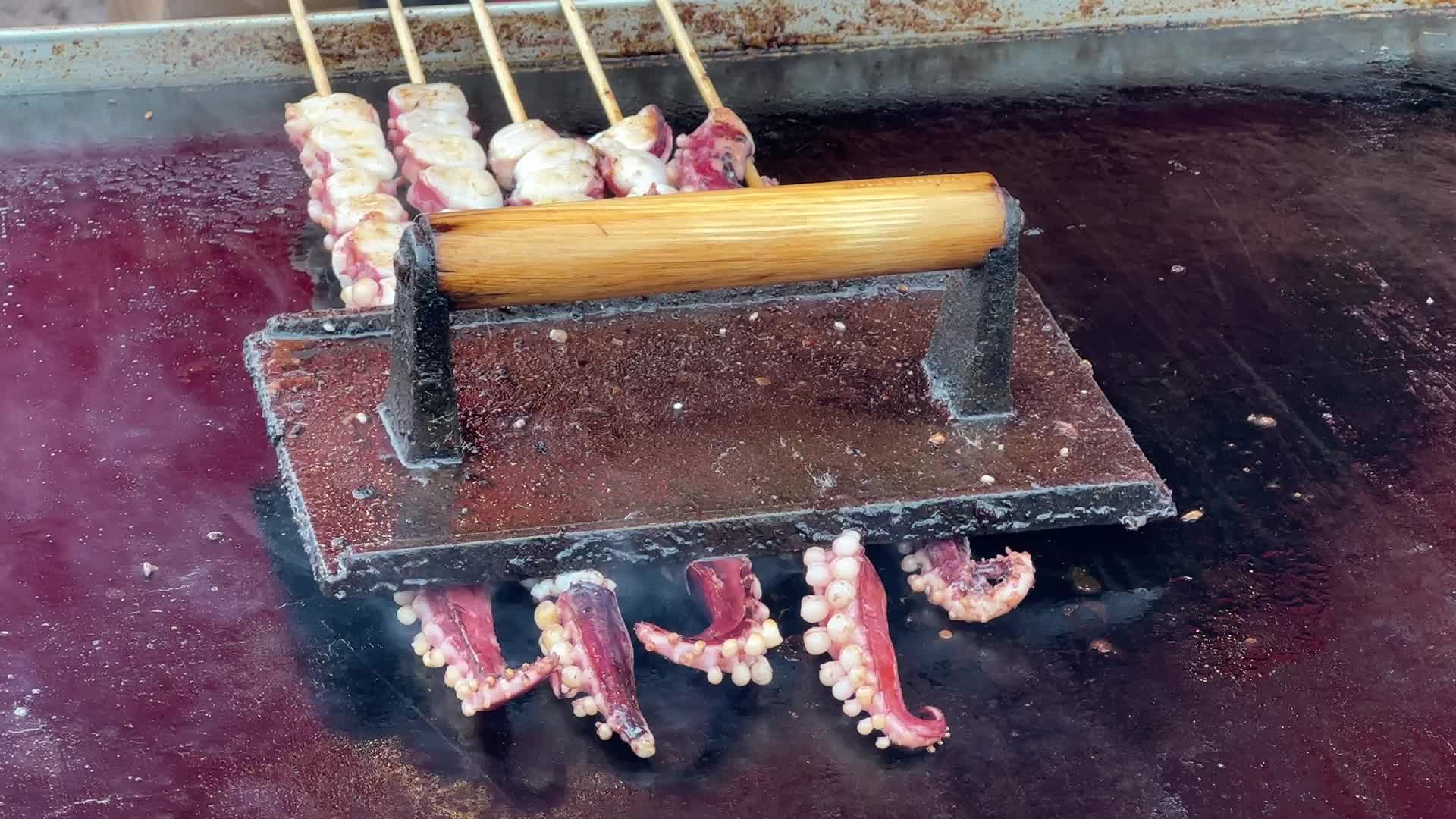Man grills skewers of octopus tentacles