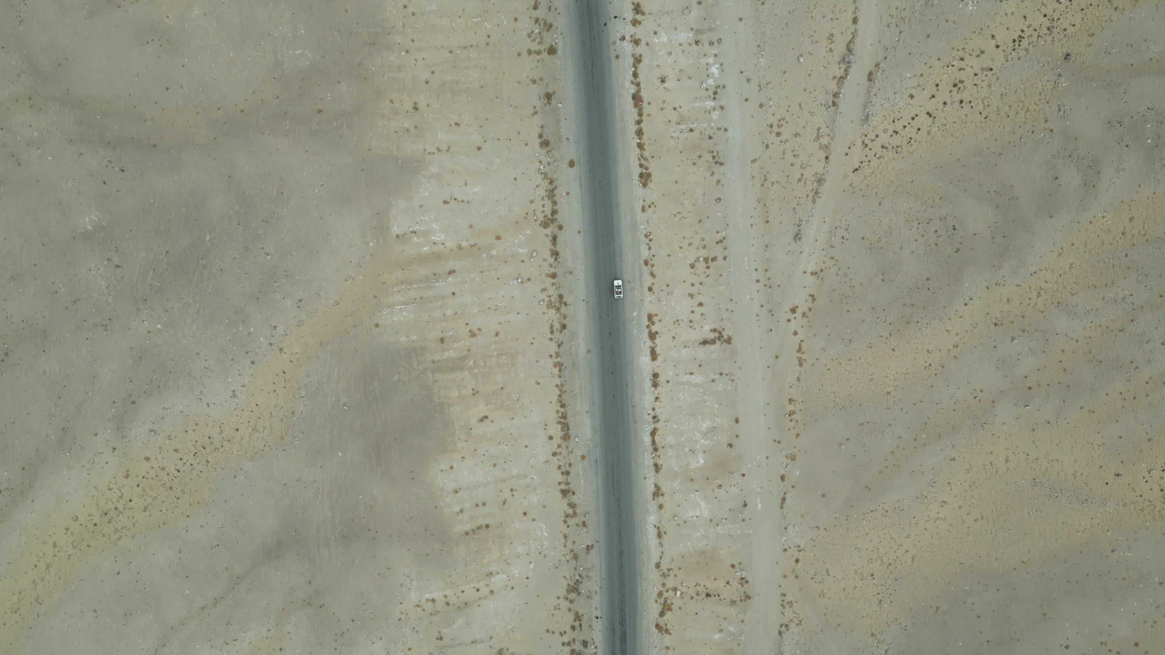 Drone shot of a small car driving on the pamir highway