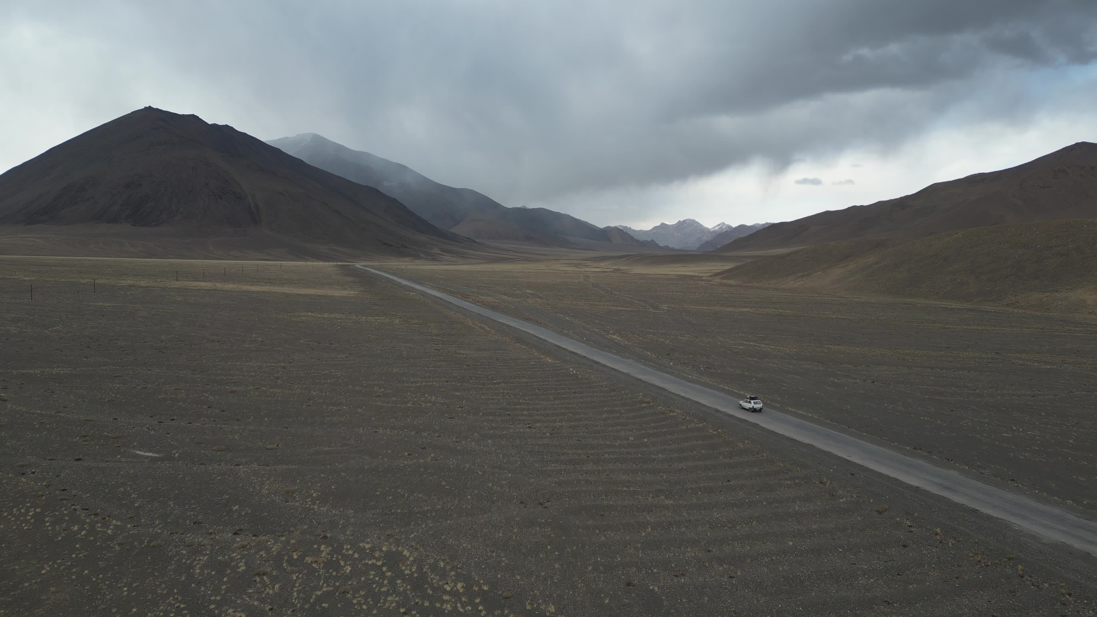 Drone shot of a small car driving on the pamir highway