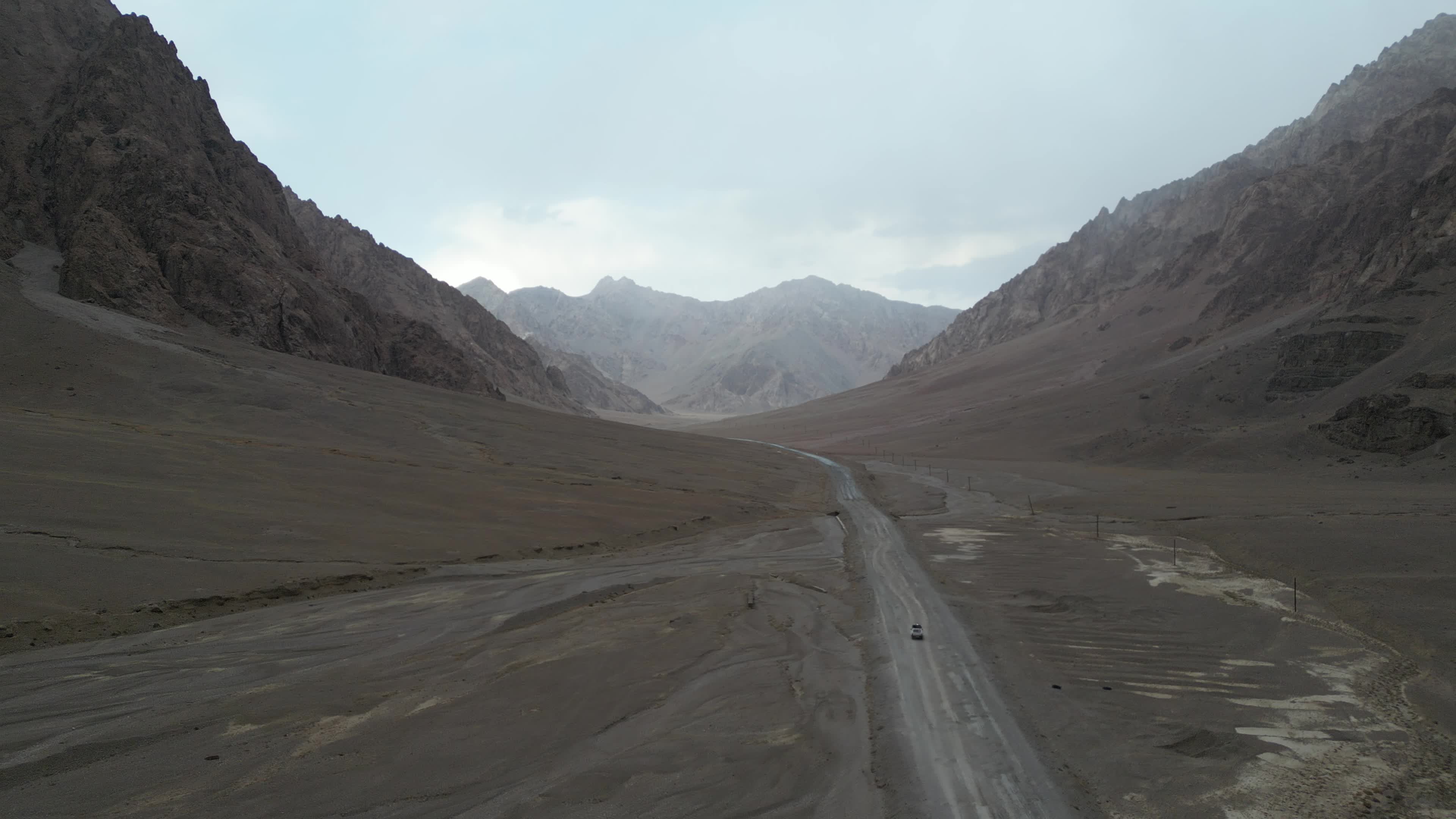 Drone shot of a small car driving on the pamir highway