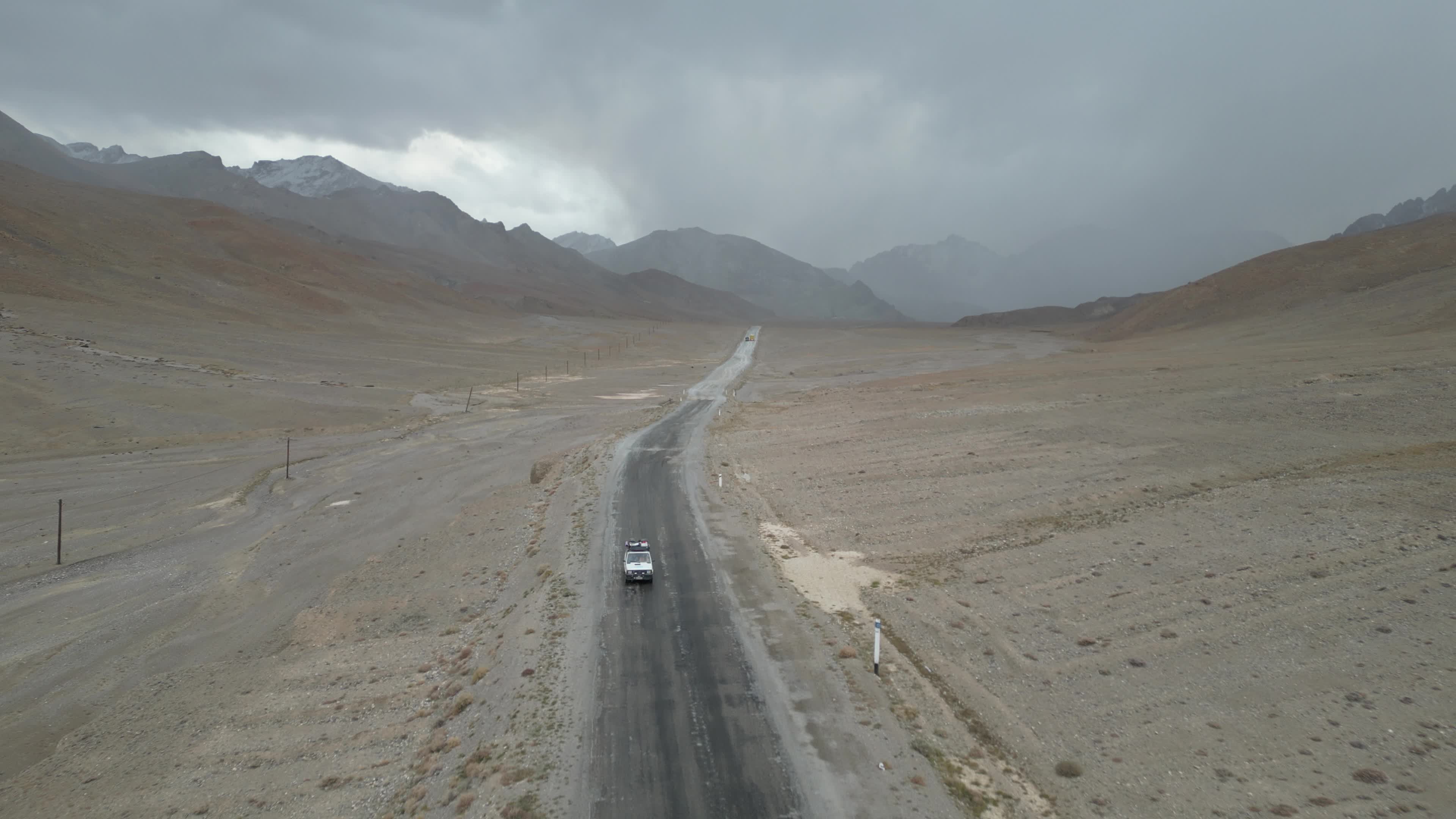 Drone shot of a small car driving on the pamir highway