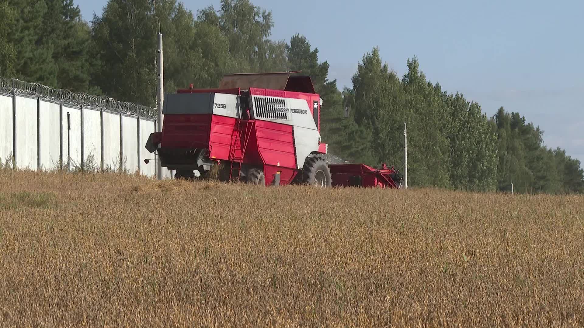 Harvester near a metal fence on the Polish border with Belarus