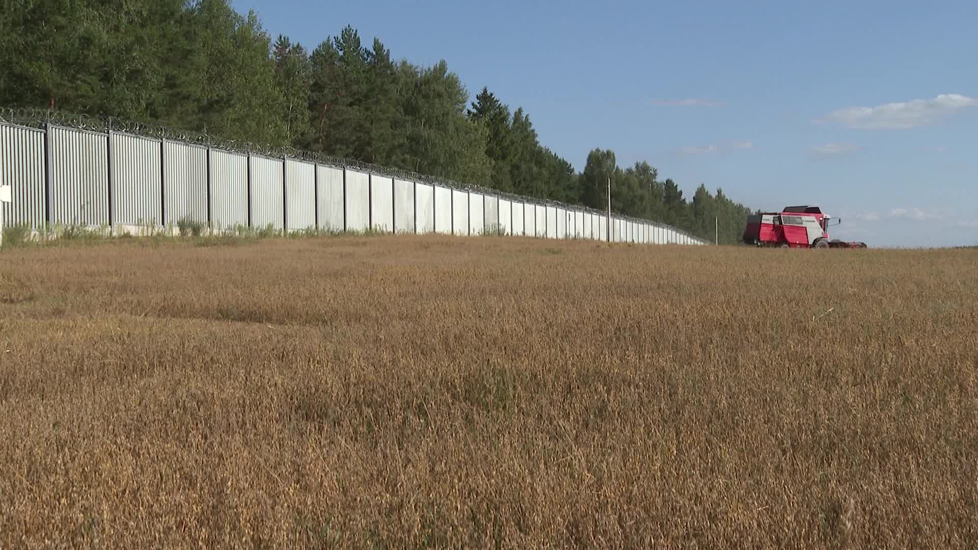 Harvester near a metal fence on the Polish border with Belarus
